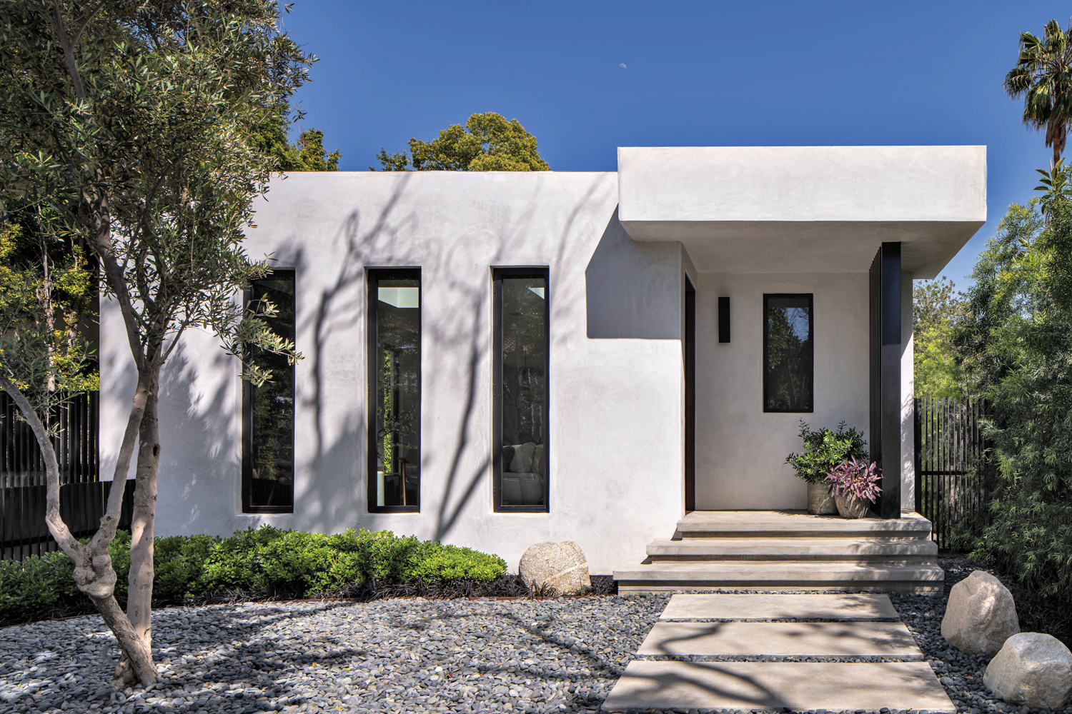 facade of white minimalist home with slit windows and a gray pebbled lawn by Jason Kalman