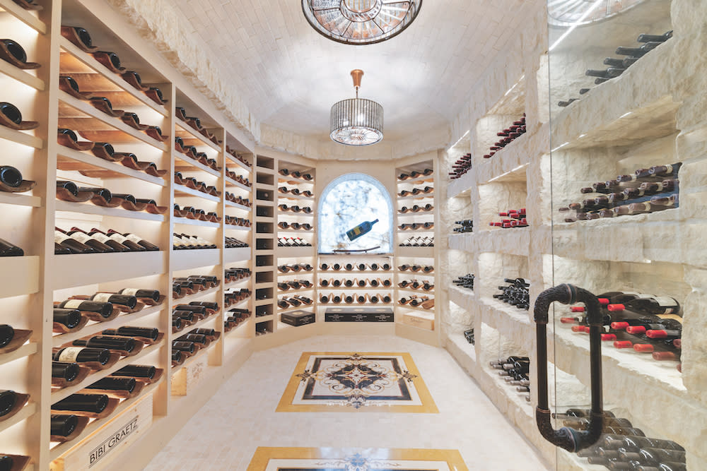 Custom wine cellar wine racks of wine on each wall, brick ceiling and two decorative chandeliers.