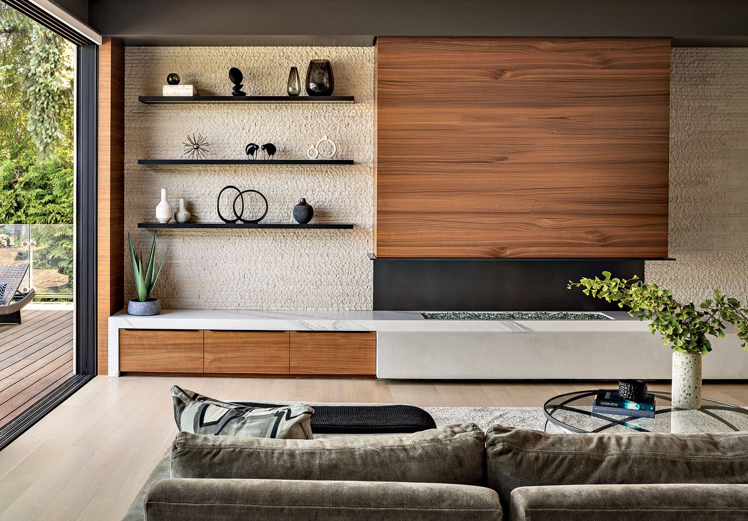 A couch and table face a console with wood accents and a fire element, with shelving above.
