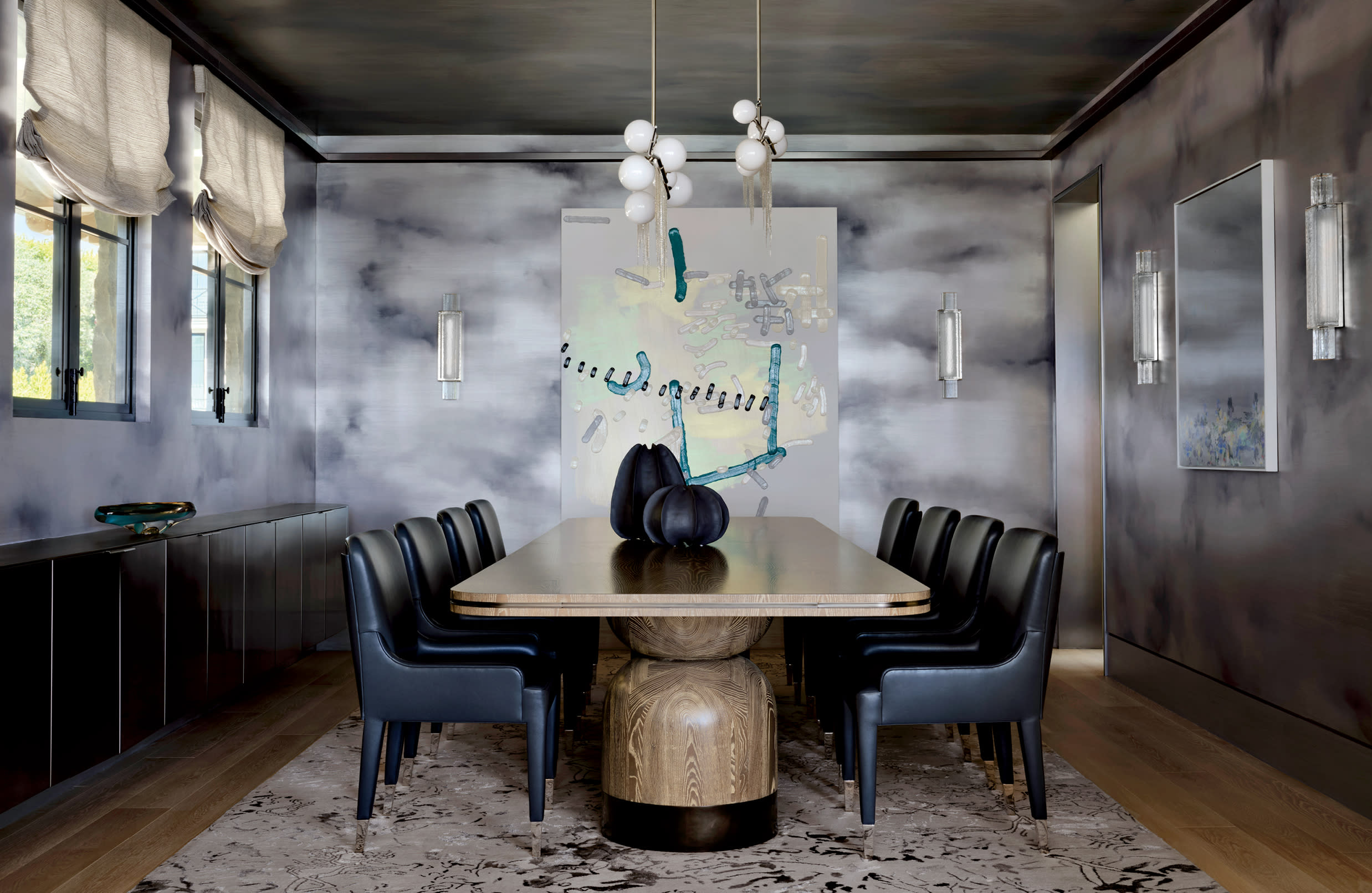 moody dining room with dark blue chairs surrounding a long wood table