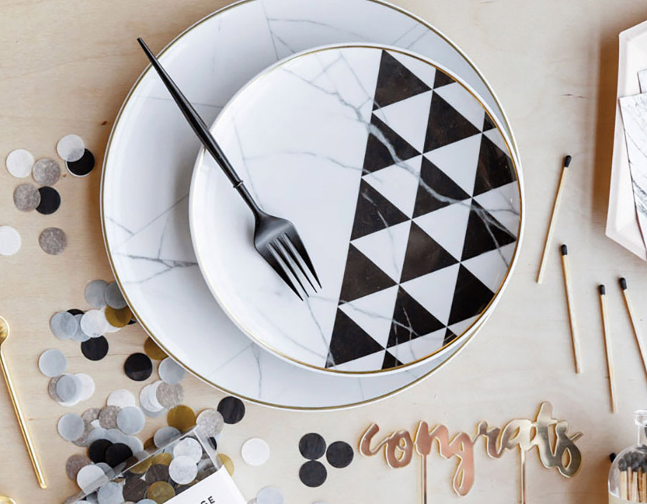 Tablescape including plate with black and white triangle pattern and confetti.