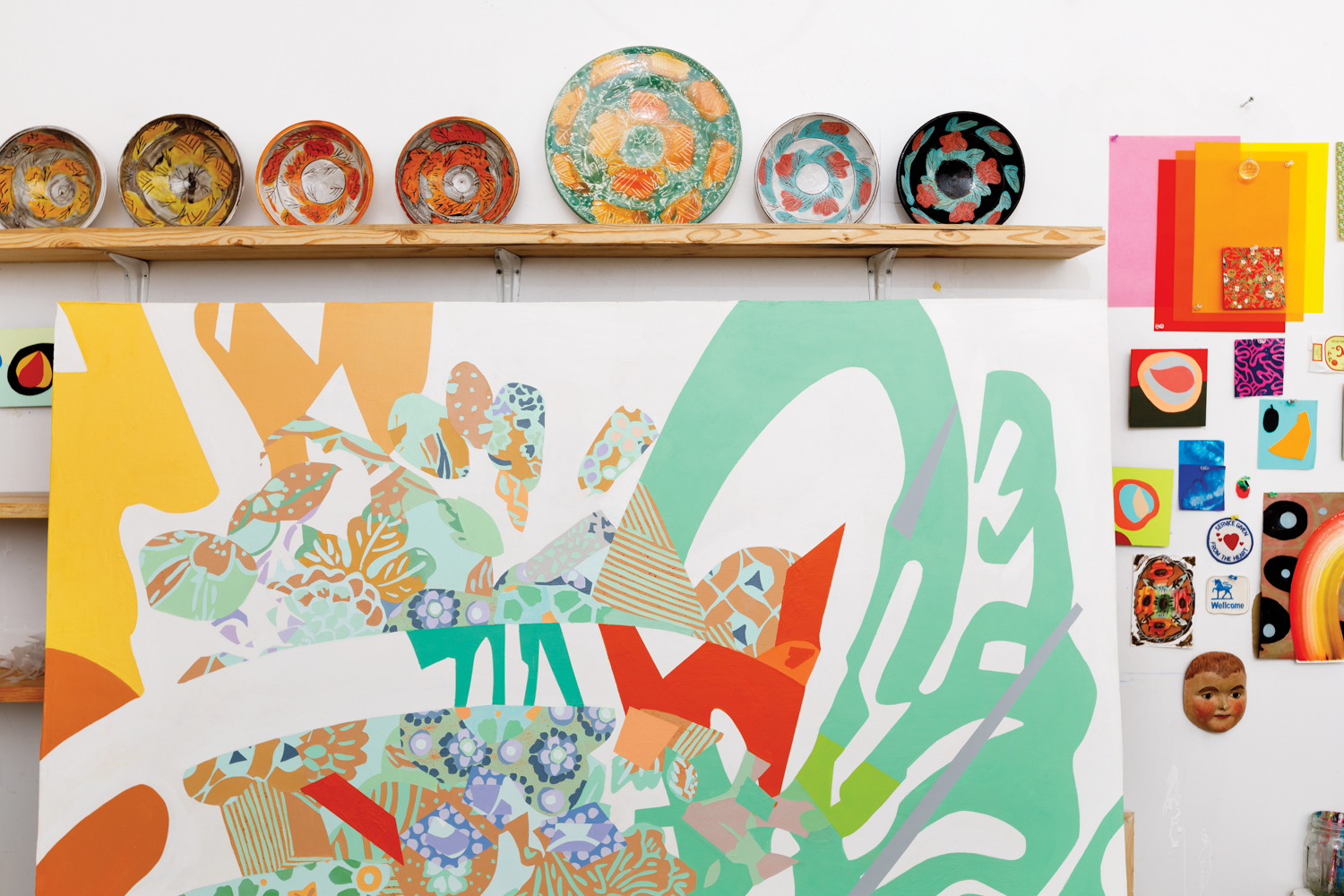 Decorative plates on a shelf above a colorful abstract painting