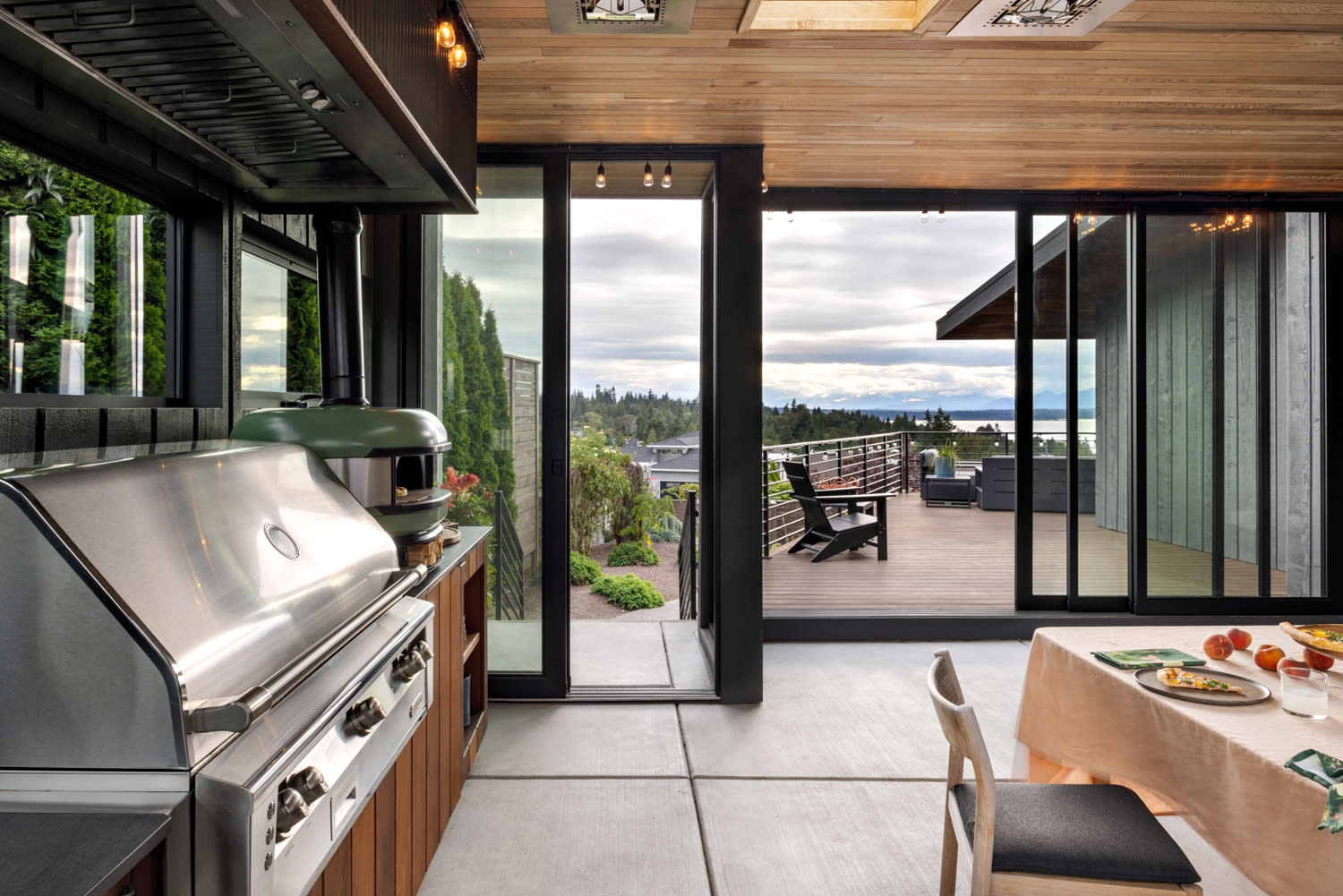A spacious alfresco kitchen featuring a grill and a dining table, designed for cooking and gathering.