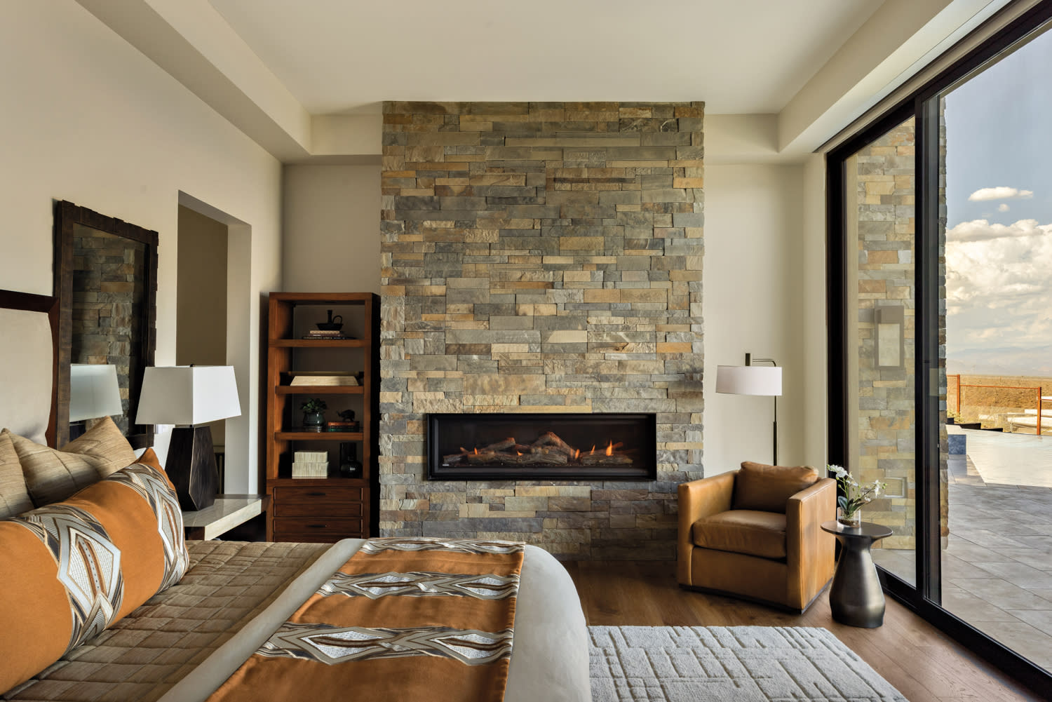 A cozy bedroom featuring a fireplace and a neatly made bed, creating a warm and inviting atmosphere.
