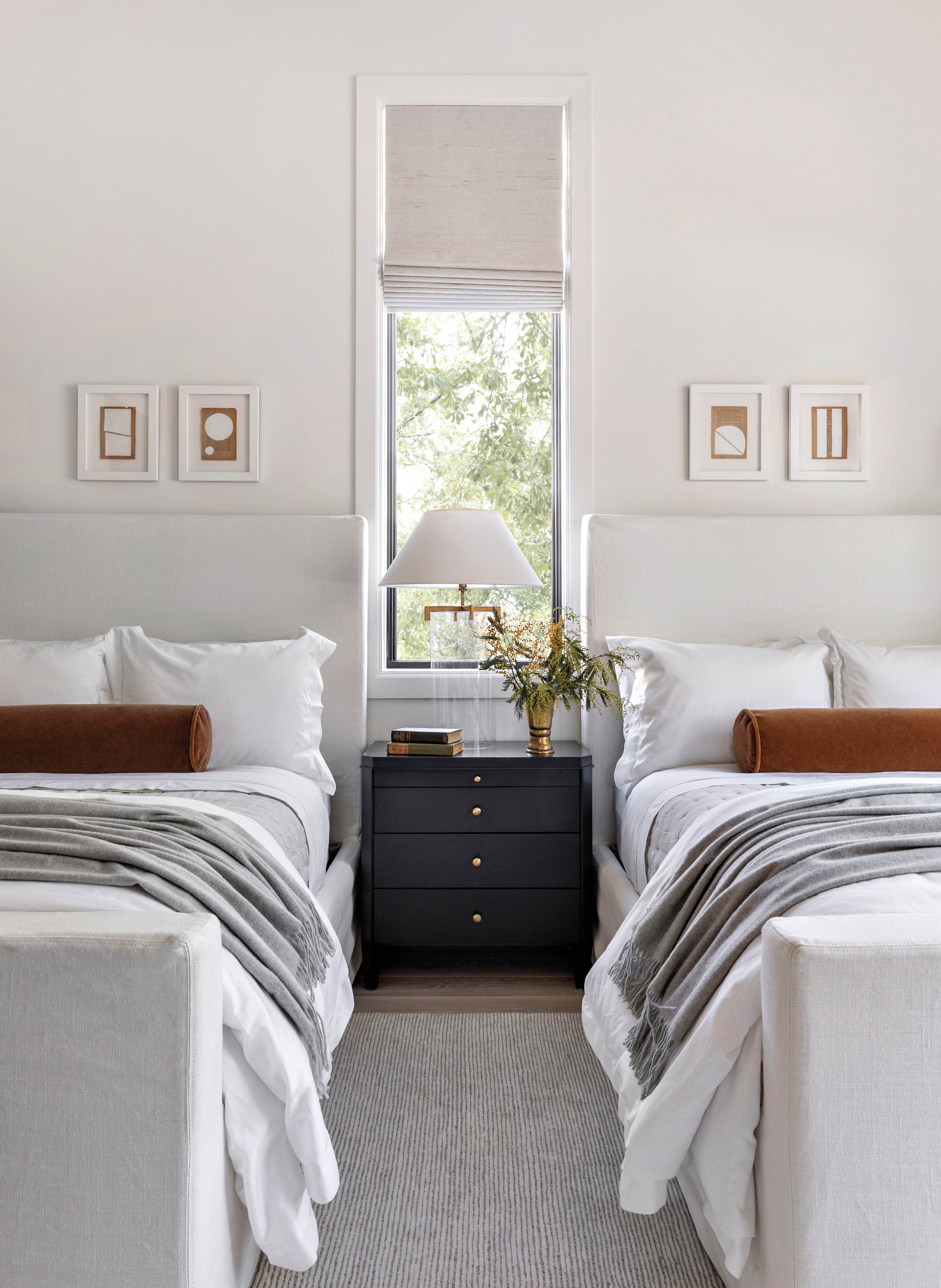 white guest room with two beds and nightstand with roman shade on window