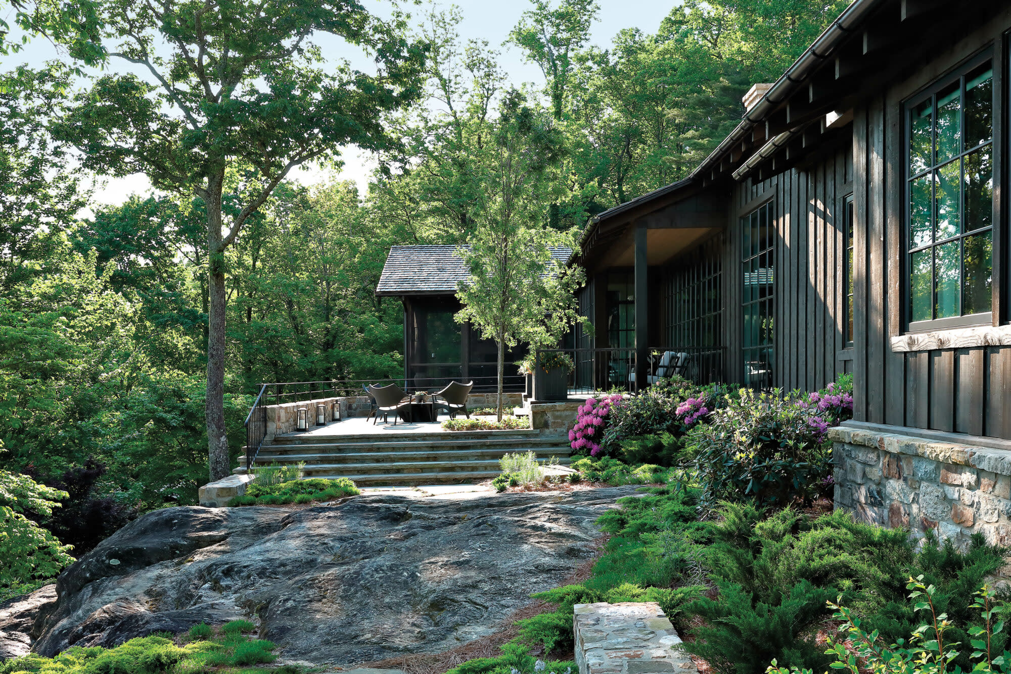 Dark-colored house by Sam Edgens on rocky cliff edge with lush landscaping