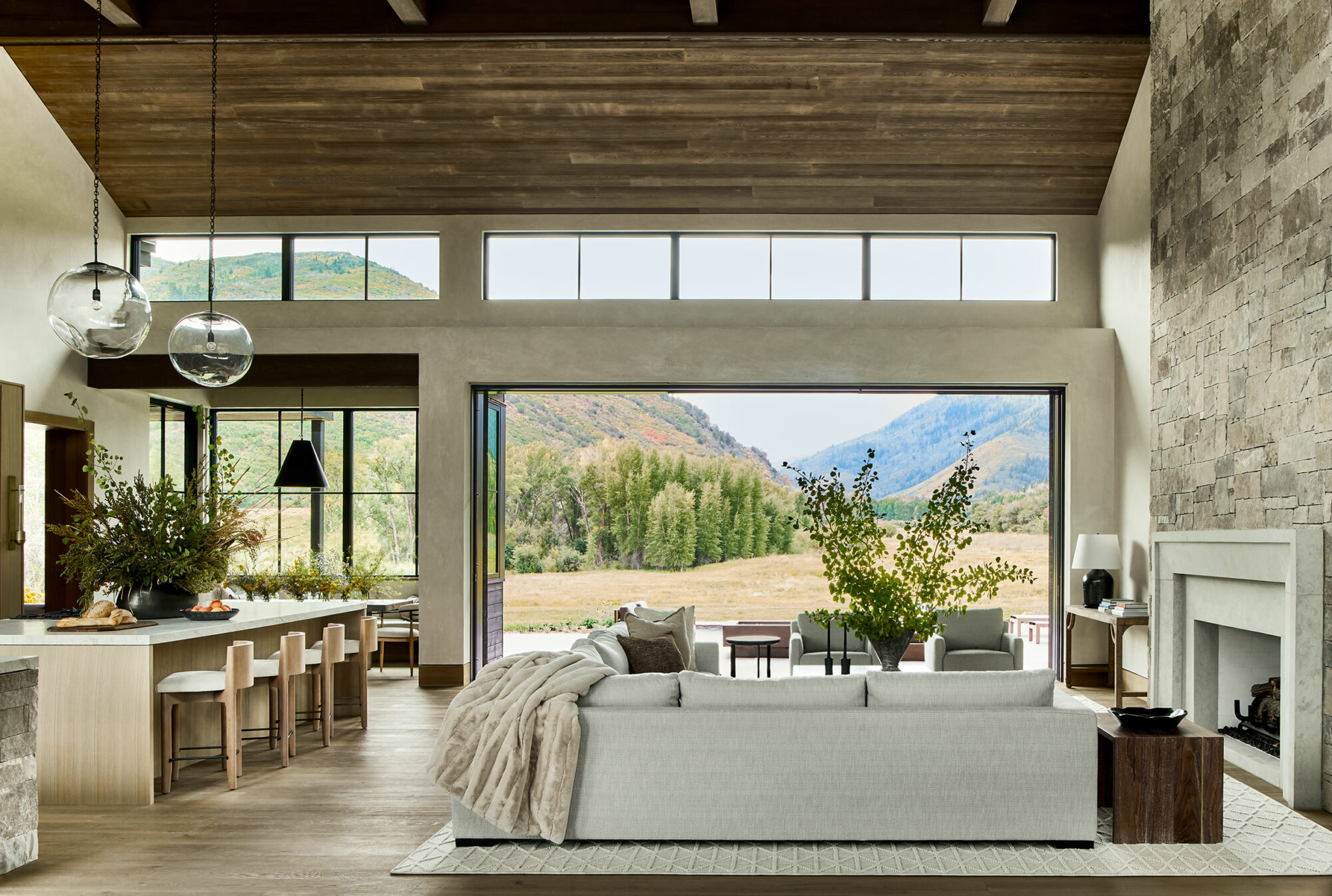 living room with sectional, fireplace, large windows, view of kitchen island and chairs