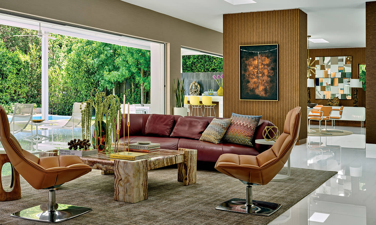 living room decorated with a dark red couch and printed pillows, sitting opposite brown leather chairs and a coffee table