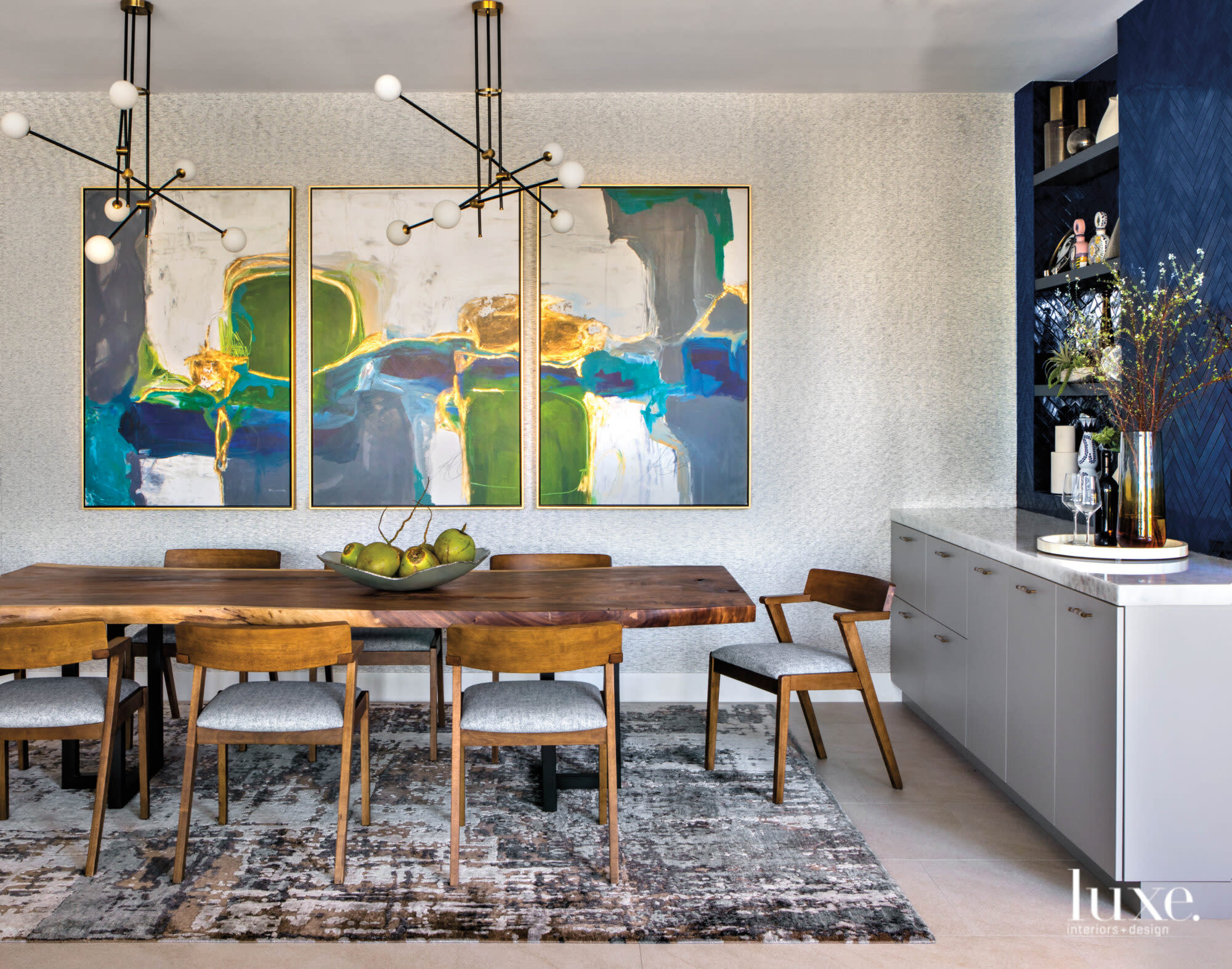 Dining room with jewel-tone artwork and wooden table and chairs.