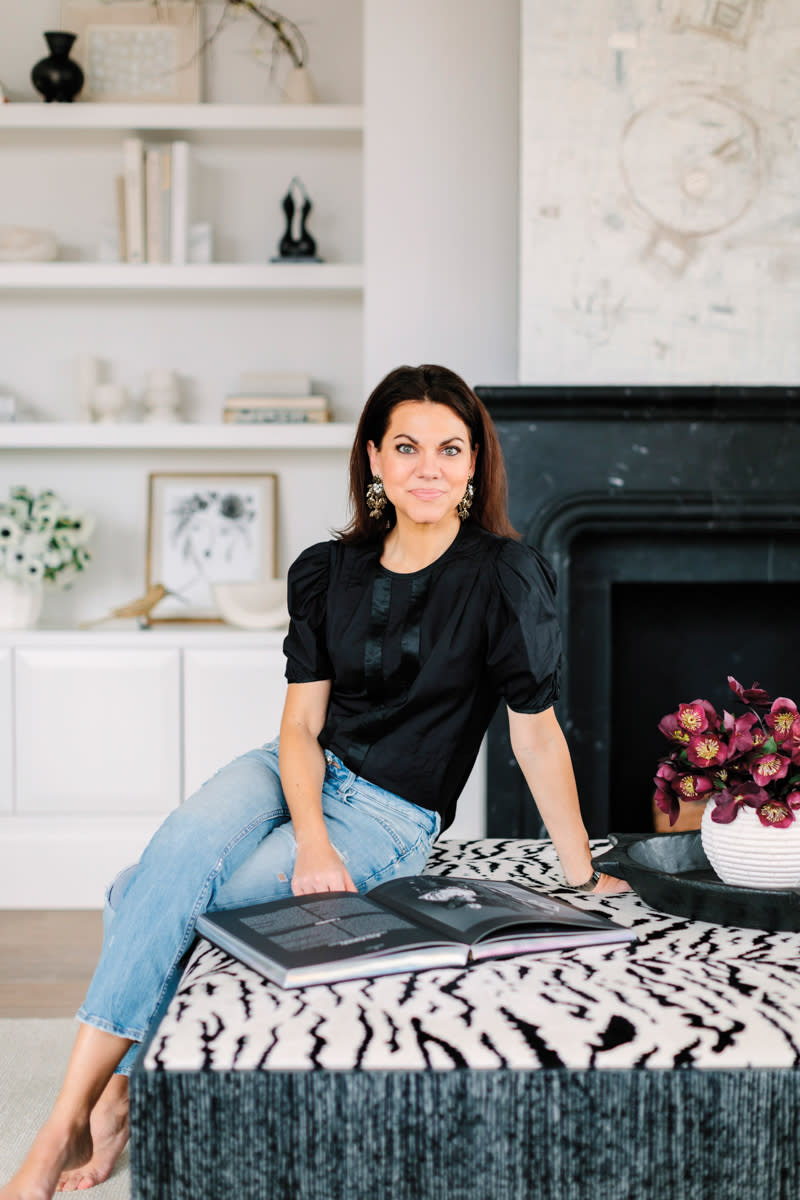 Kelly Huliman seated with book on zebra-print ottoman