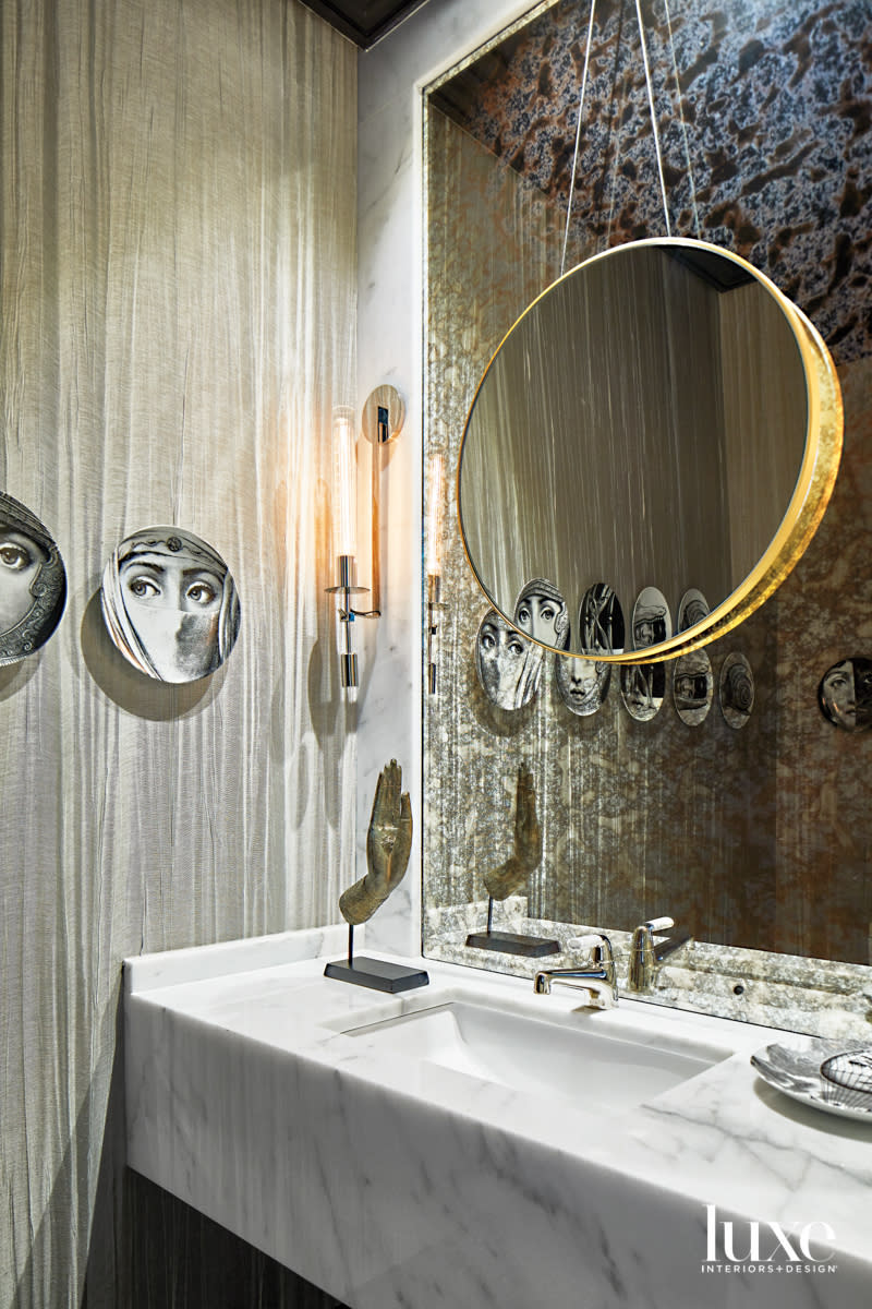 Glamorous powder room with striated gray walls, Fornasetti plates and metallic accents