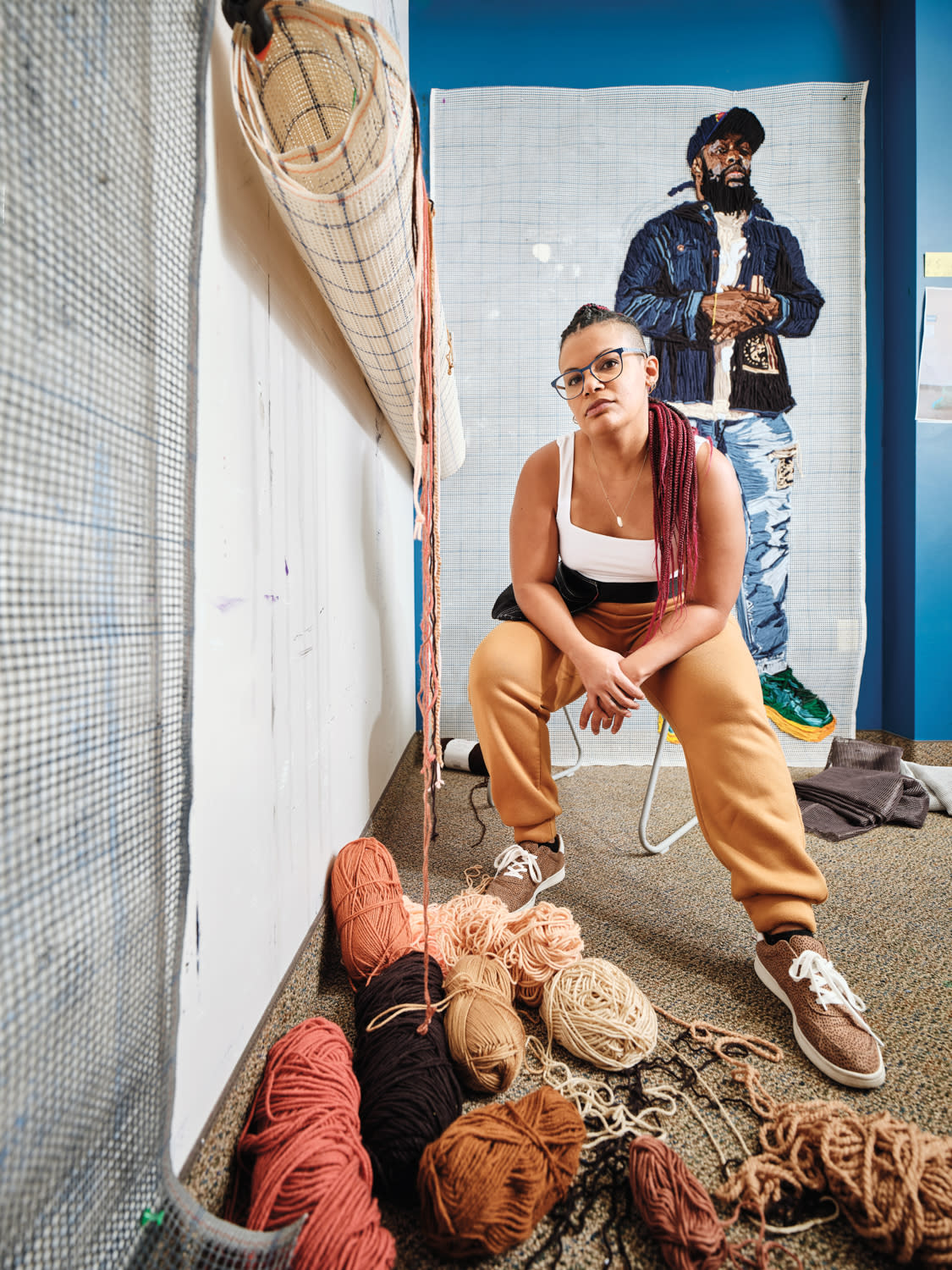 artist Kandy G Lopez sitting by her fiber work and yarn in her studio