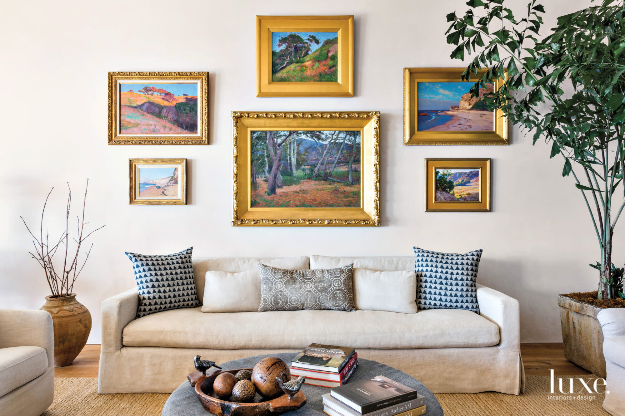 Detail shot of living room with sofa and collection of plein air paintings above