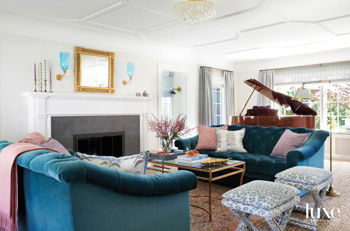 Living room view facing a fireplace with a pair of blue velvet sodas and a piano in the background