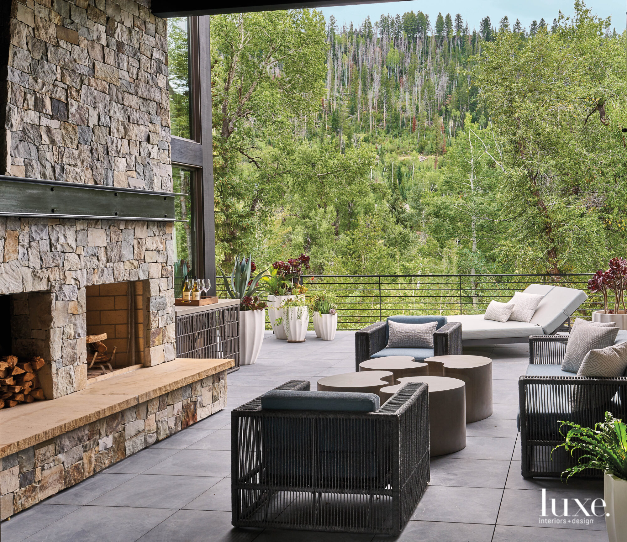 On a patio, outdoor furniture cozies up the the fireplace.