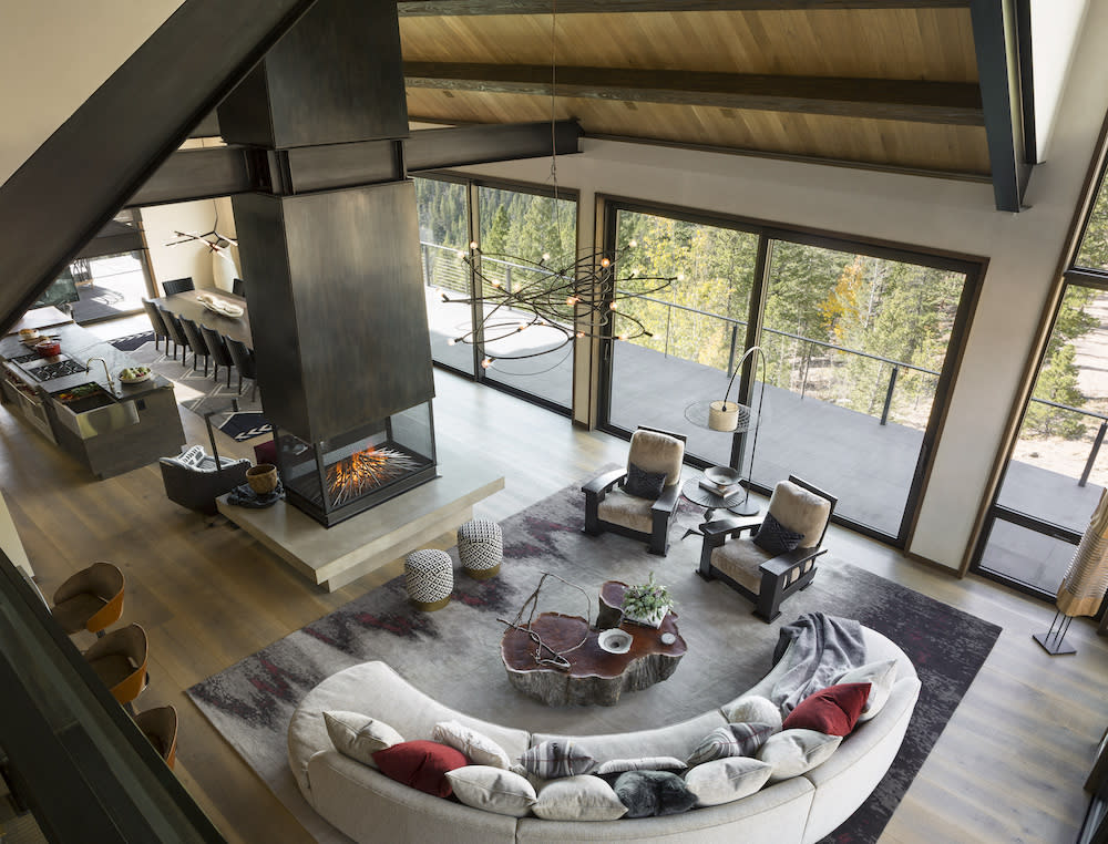 Views from above to the open entertaining space with sectional couch, fireplace and sculptural lighting