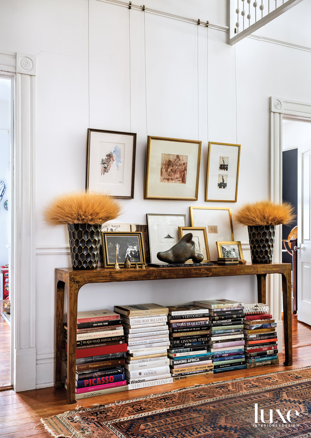 Wooden console table with lots of framed artwork and books