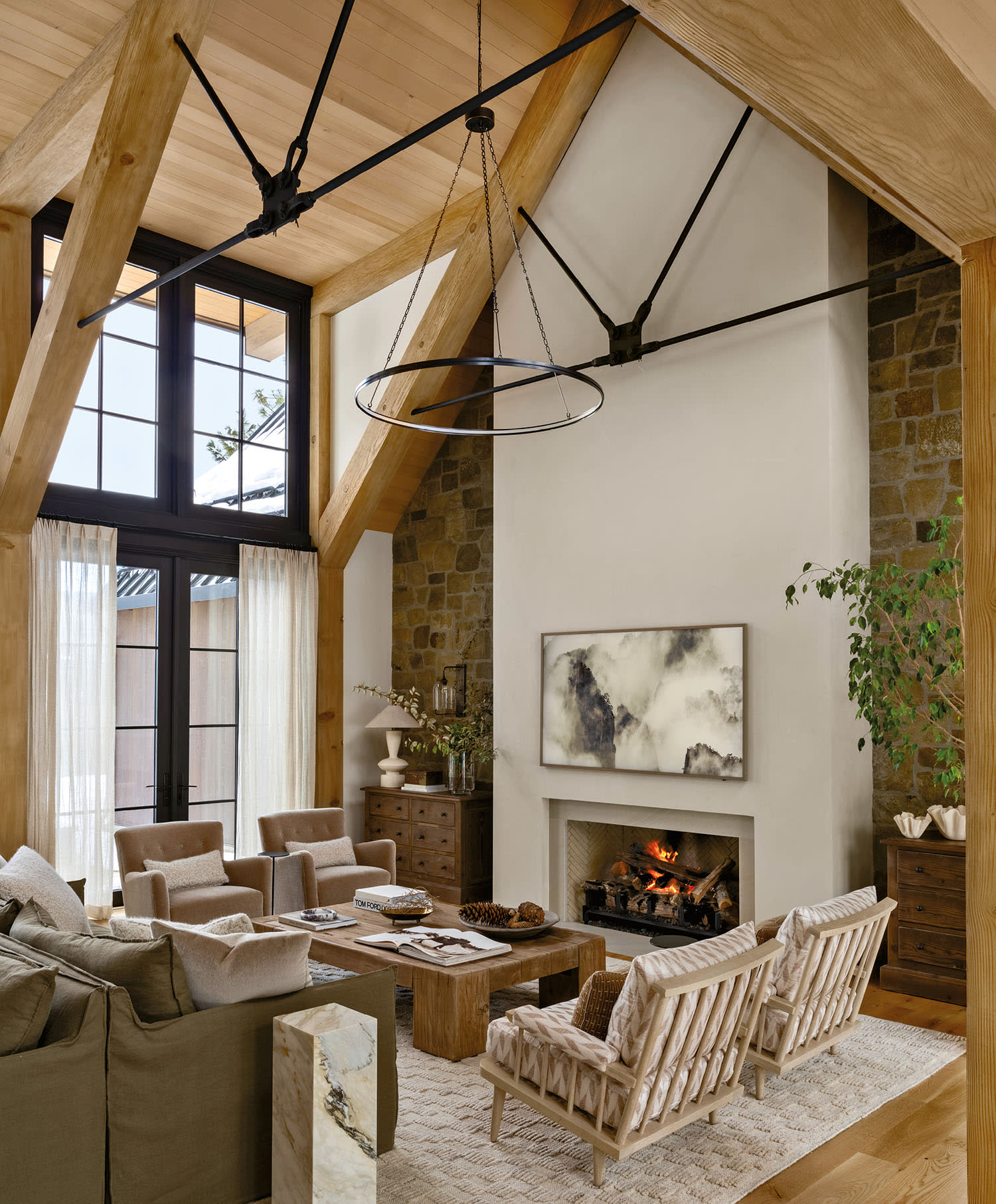 Spacious living room with high wooden beams, large windows, and a stone fireplace.