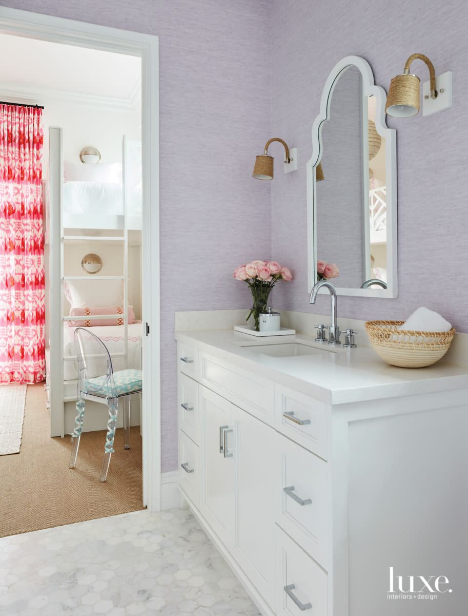Bathroom with lavender wallcovering and white vanity.
