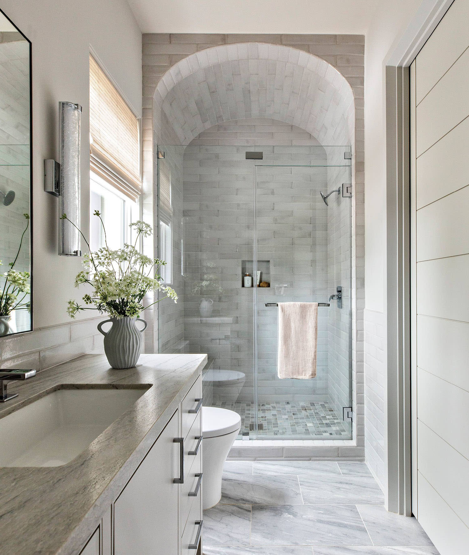 bathroom with a barrel-vaulted shower and marble-topped vanity