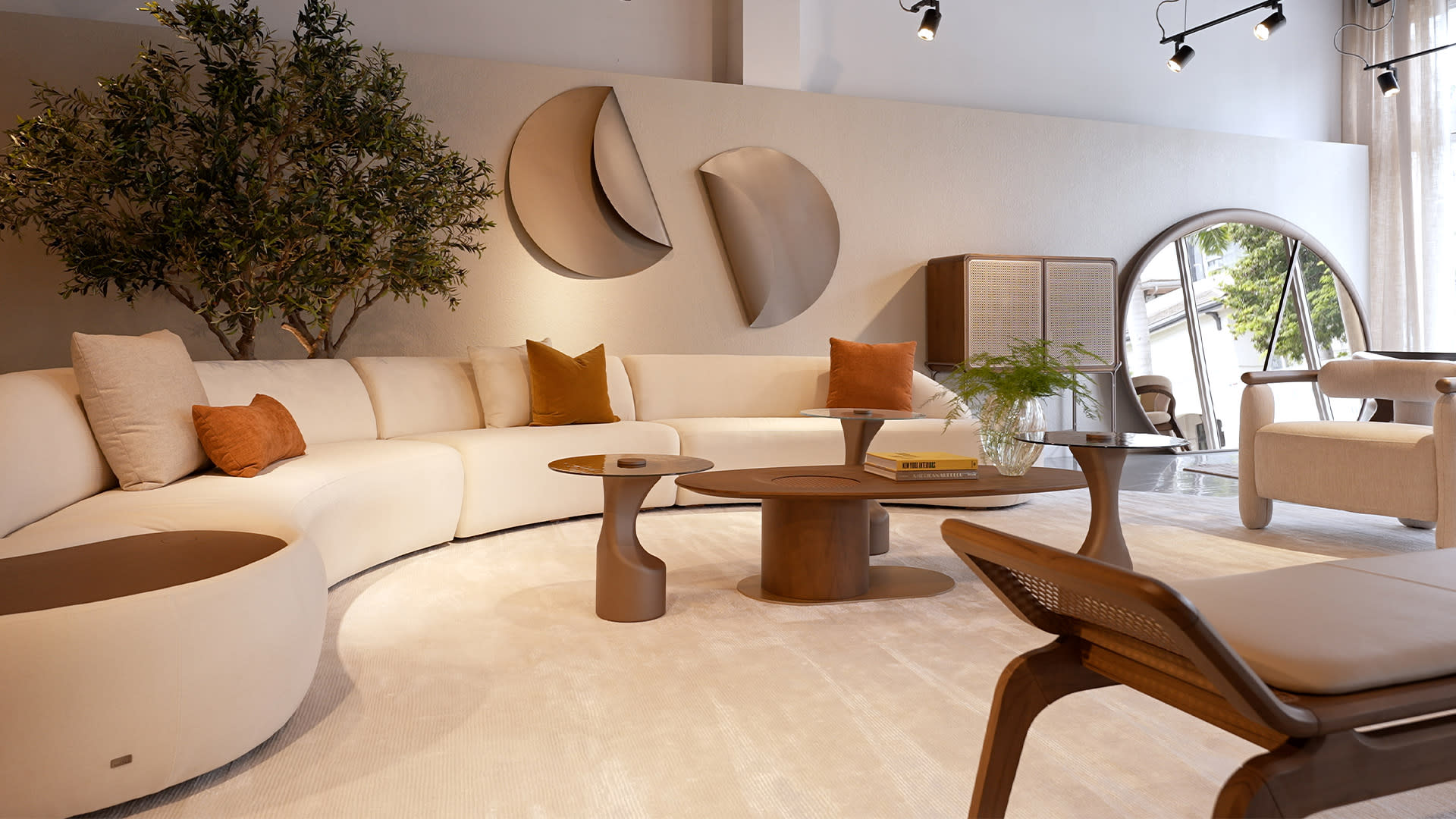 Modern living room with curved beige sofa, orange pillows, and circular wooden tables