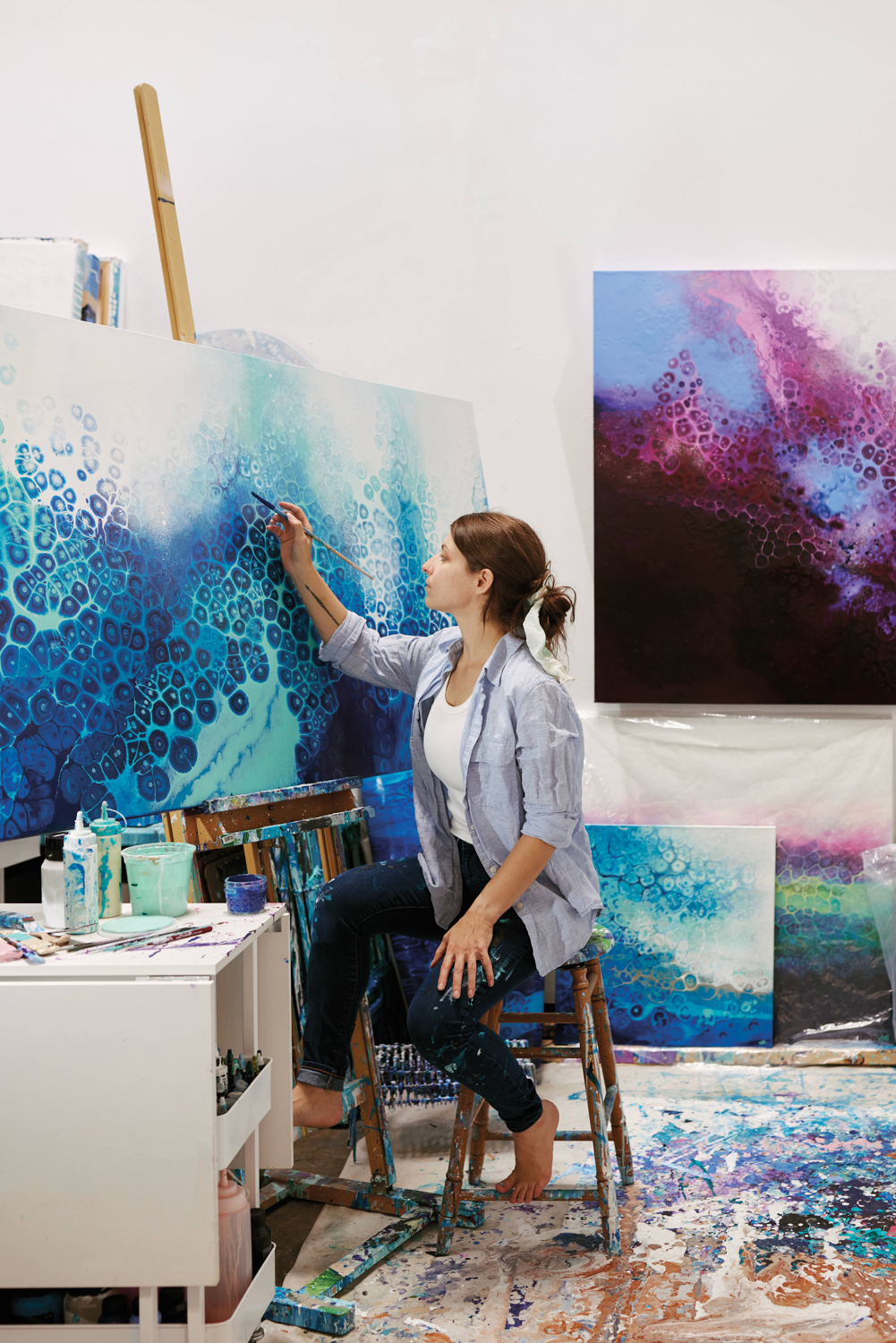 Shaylen Amanda Broughton paints on a large canvas in her art studio