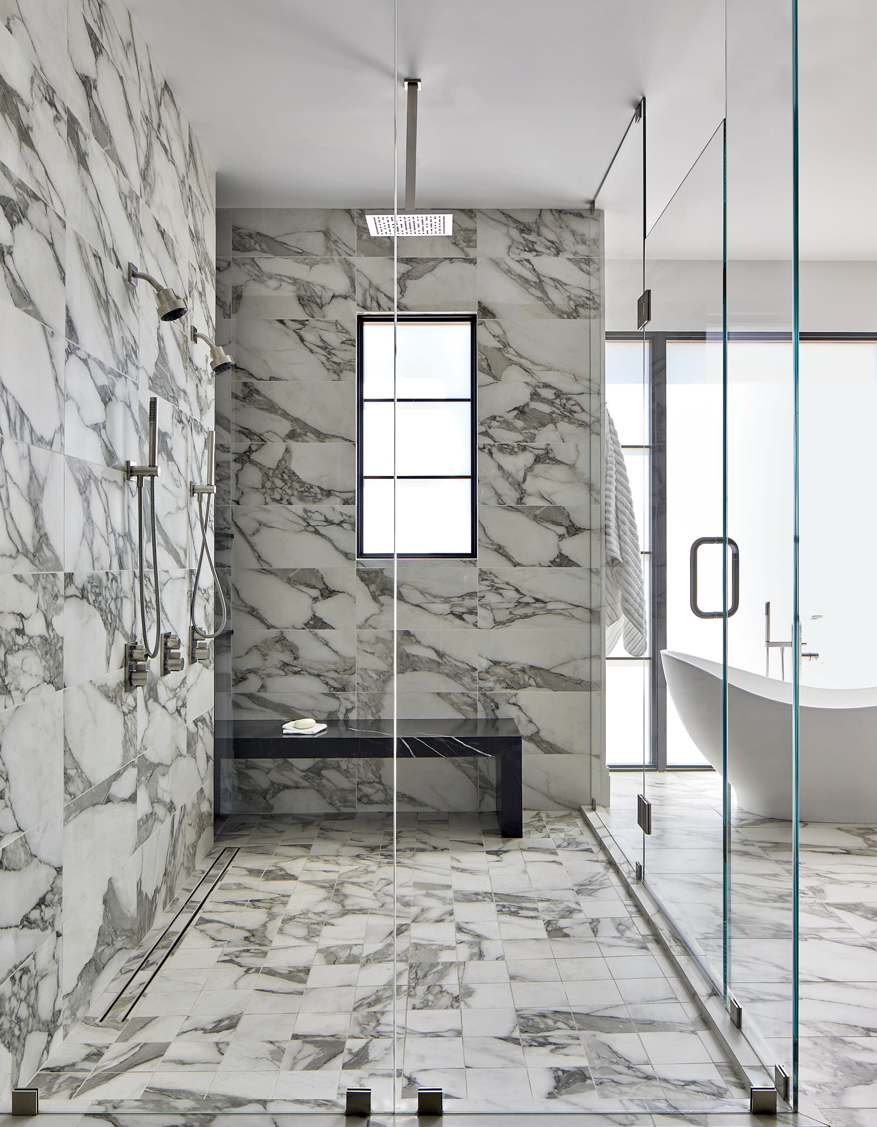 porcelain tile with marble effect in large glass shower with freestanding tub sitting outside 