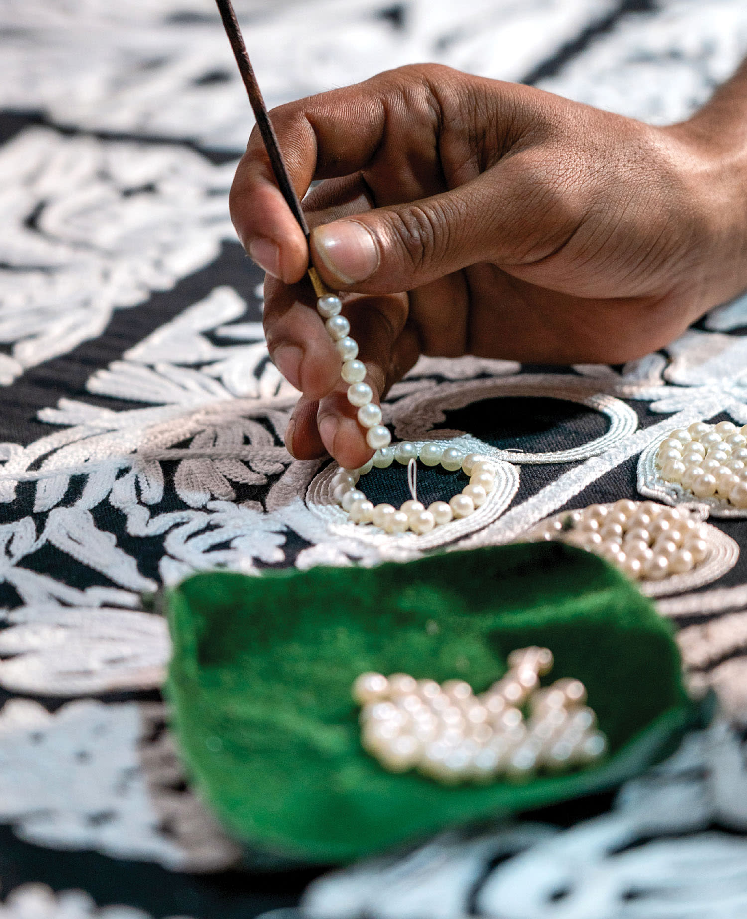 a person hand-applies pearl beads on Arte's Le Perle wallcovering