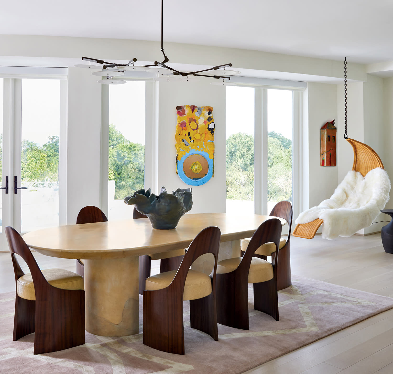 modern dining room with a sculptural dining set flanked by a crescent-shaped hanging chair