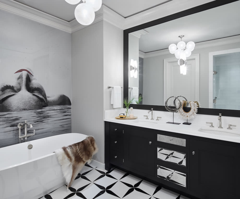 Black and white primary bath. Black cabinet with white countertop, dual sinks, large mirror, free standing tub, black and white floor tiles.