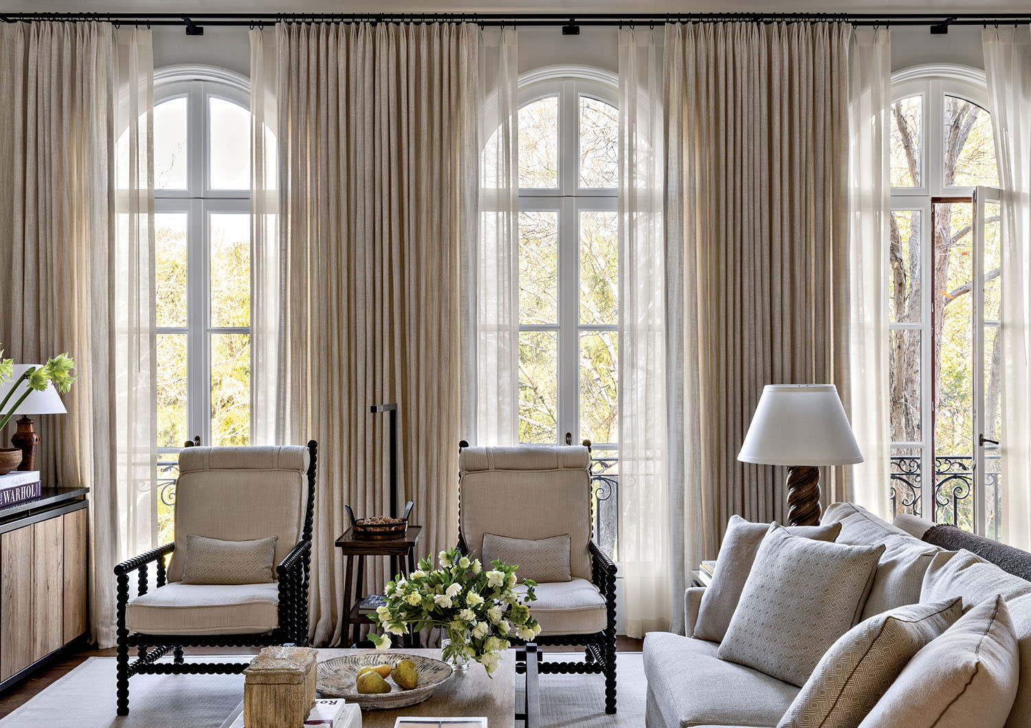 formal family room with arched windows and beige drapery