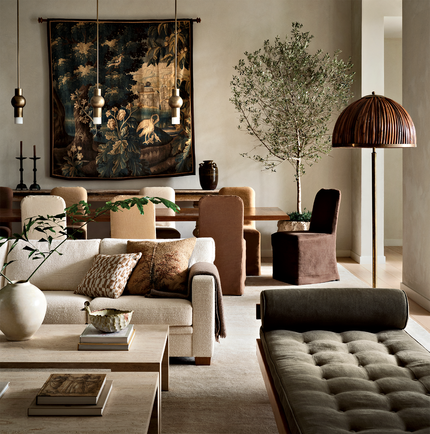 A living space with tan and olive couches arranged around a coffee table, with a dining room behind.