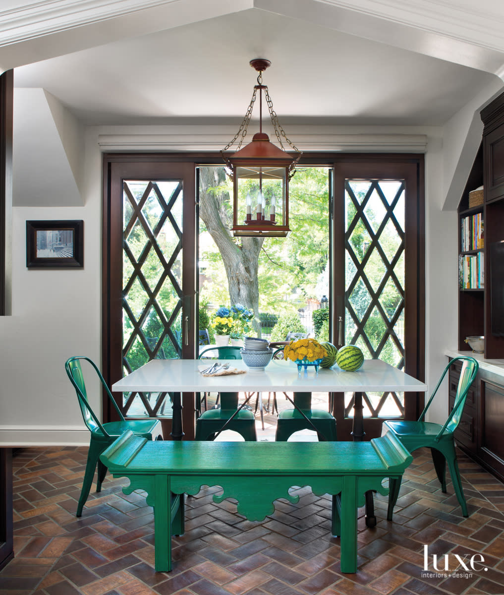 A seating area in the kitchen features a table and green chairs and benches.