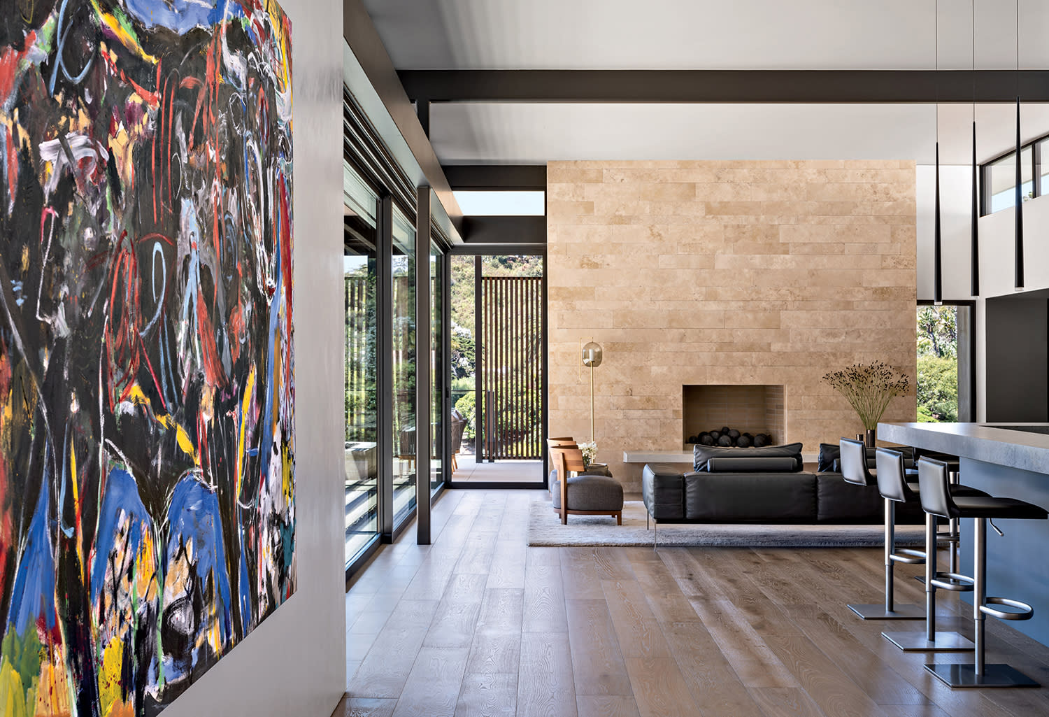 A Damian Elwes canvas fills a wall leading into the great room with a travertine fireplace surround