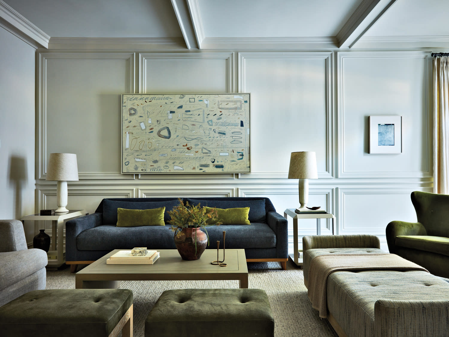 living room with warm white paneling, blue sofa and other furnishings by Joan Enger