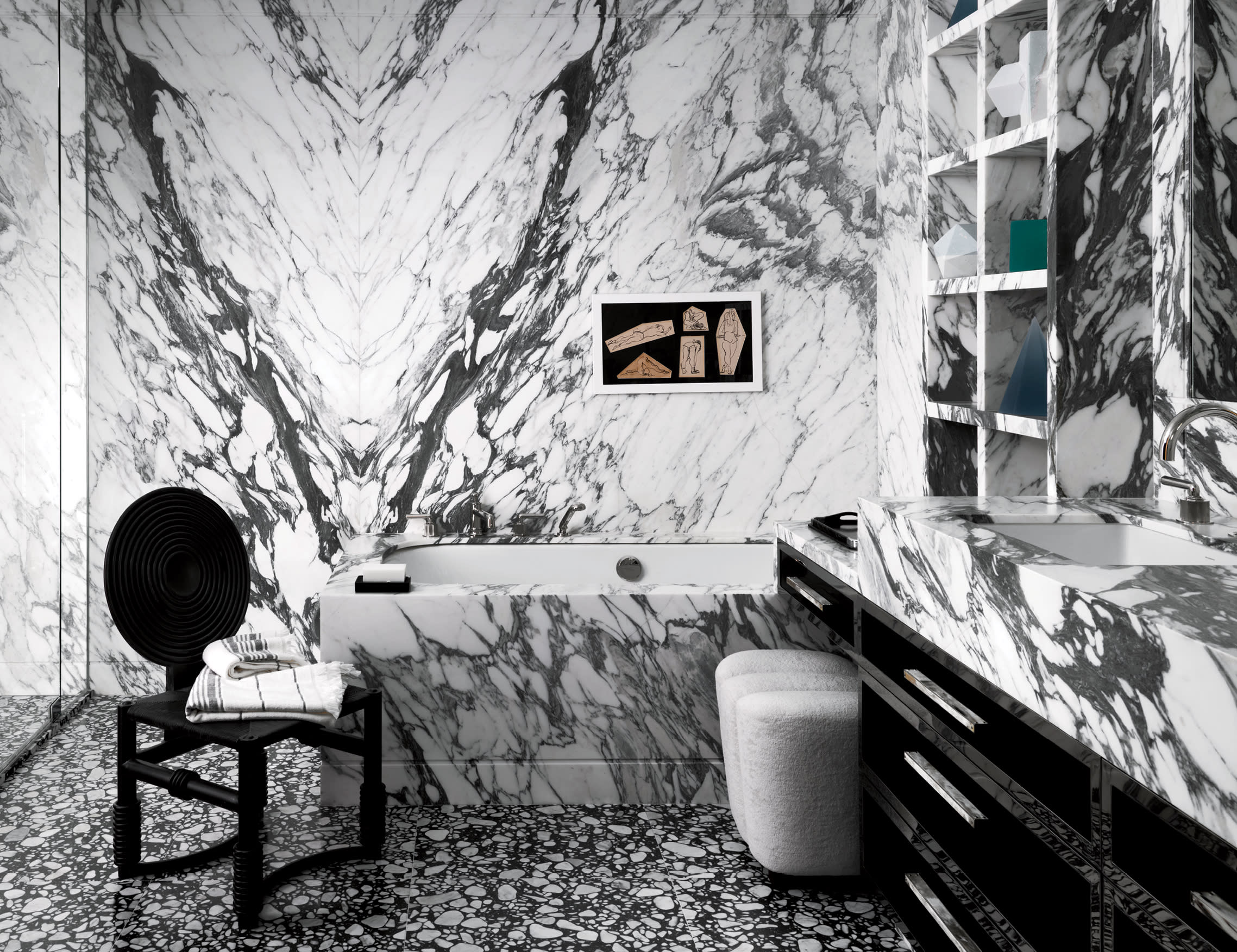 Arabescato marble flows across multiple surfaces of a bathroom with a vintage artwork above the tub