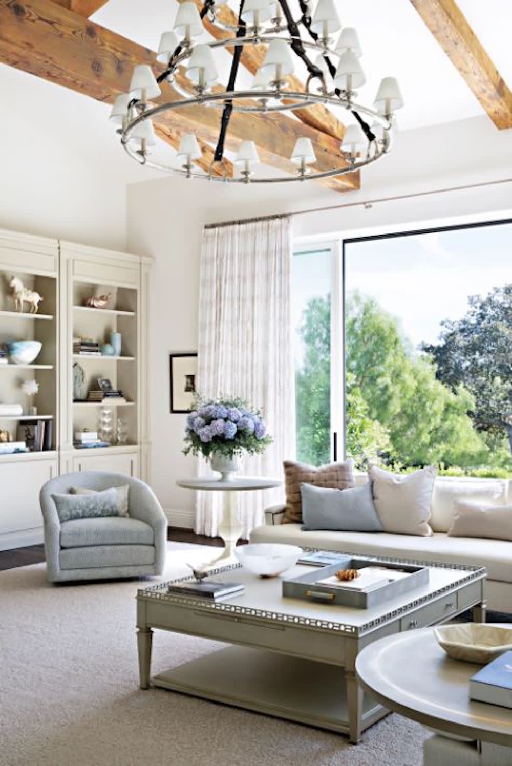 Modern living room featuring white furniture, wood beams and circular chandelier.