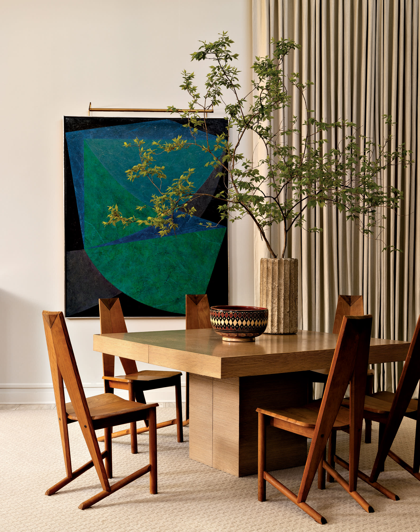 vintage white oak dining table and angular chairs across from an abstract artwork