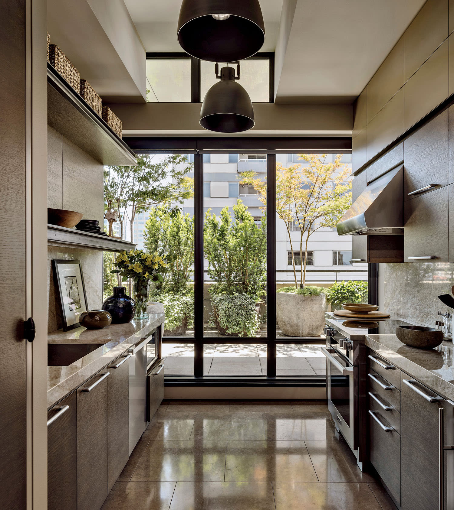 Modern kitchen featuring large floor-to-ceiling windows overlooking a garden.