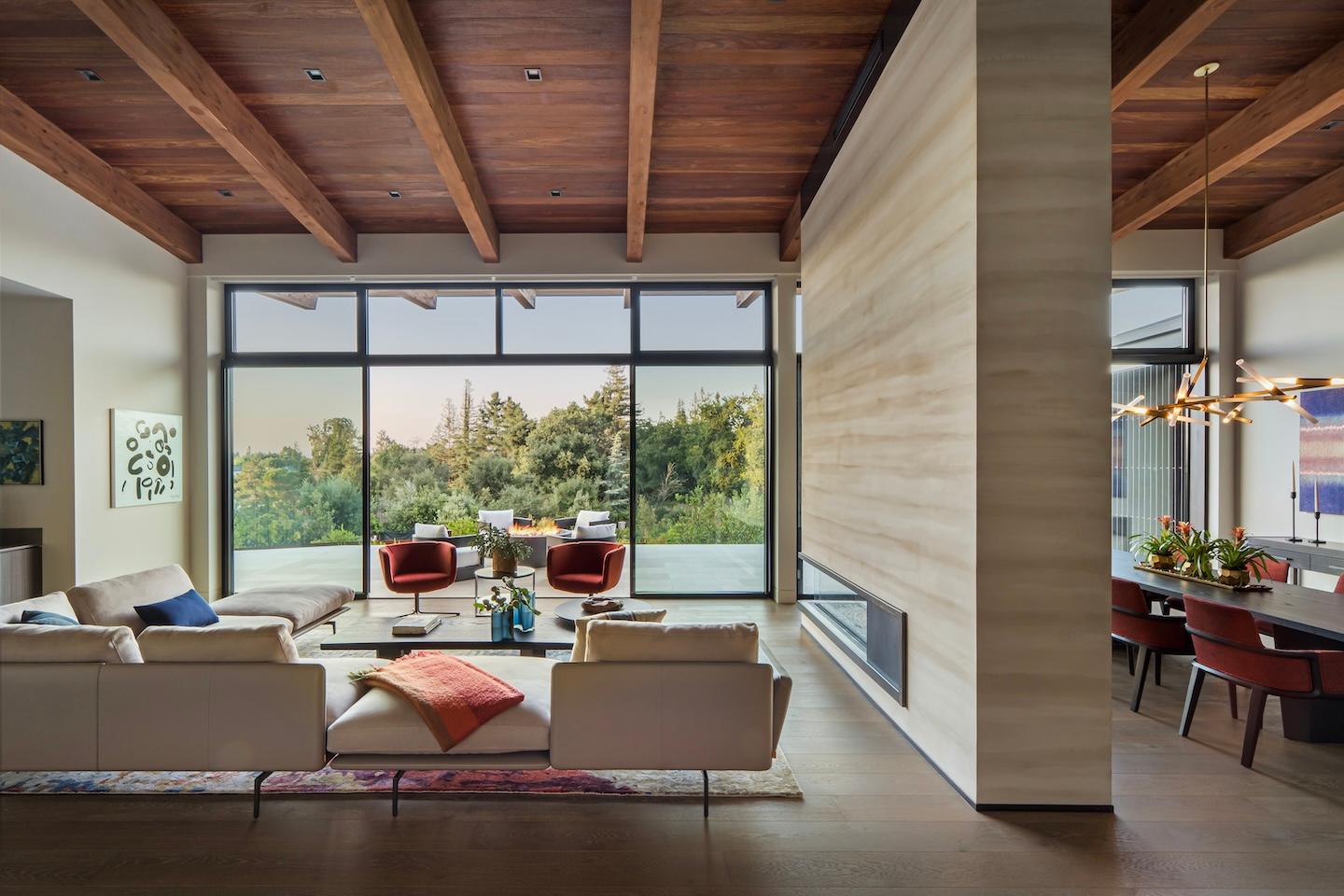 Wooden ceiling and large windows with sleek fireplace built by Conrado Home Builders.