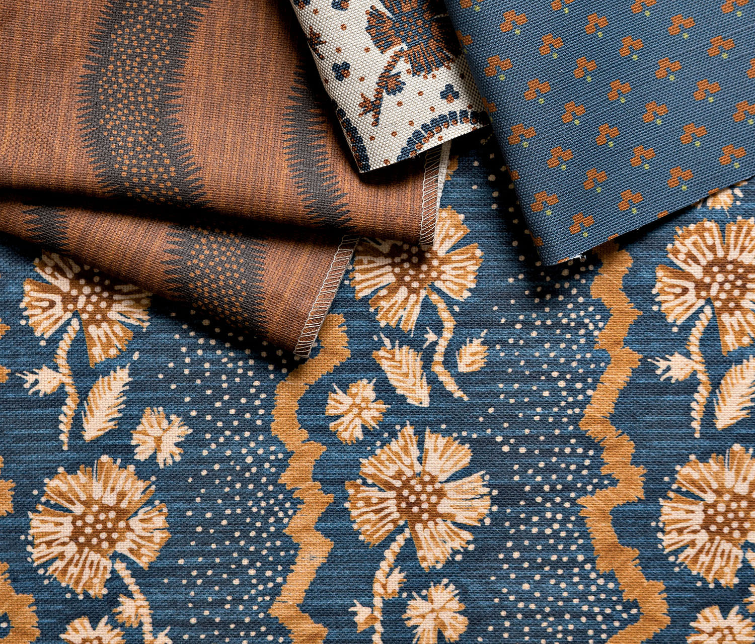 Four textiles in different blue and brown-toned patterns sit next to one another.