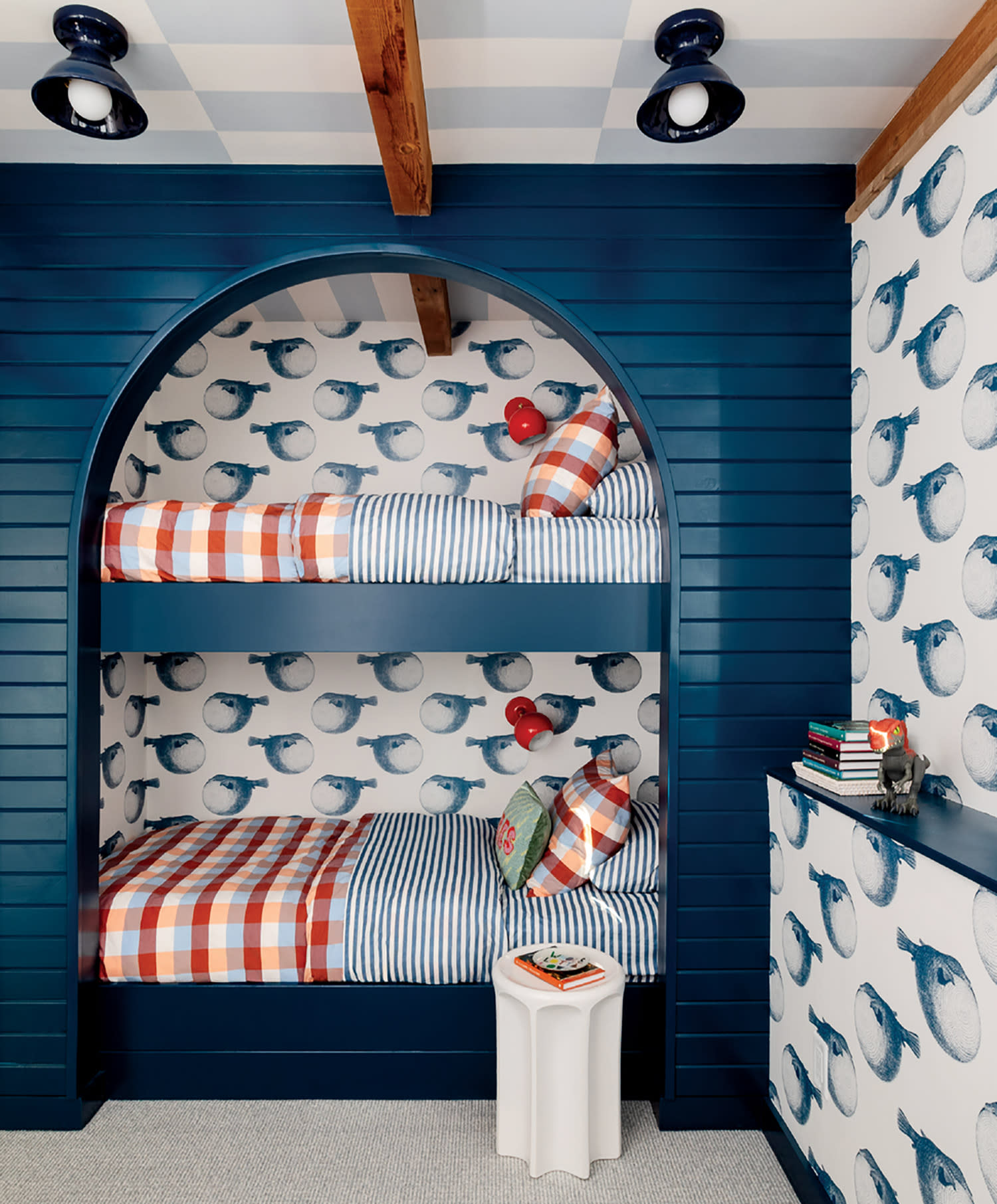 Kid's room with blue bunk beds and playful fish-patterned wallpaper. Bedding features red checkered designs. 