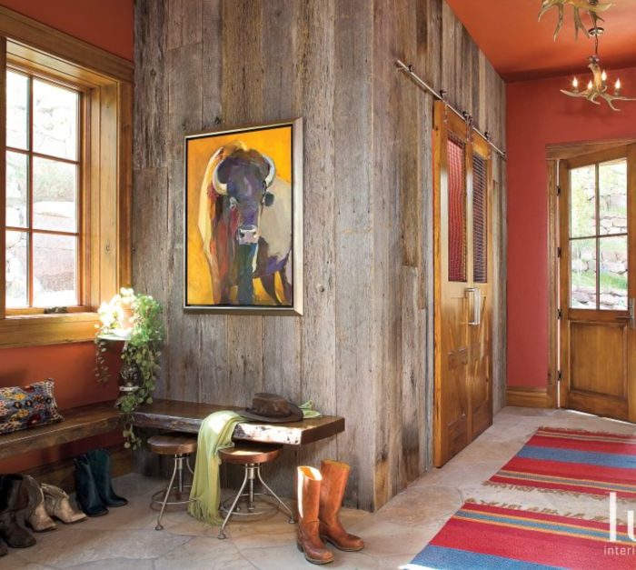 barn door hides laundry room in colorful rustic mudroom with red accents