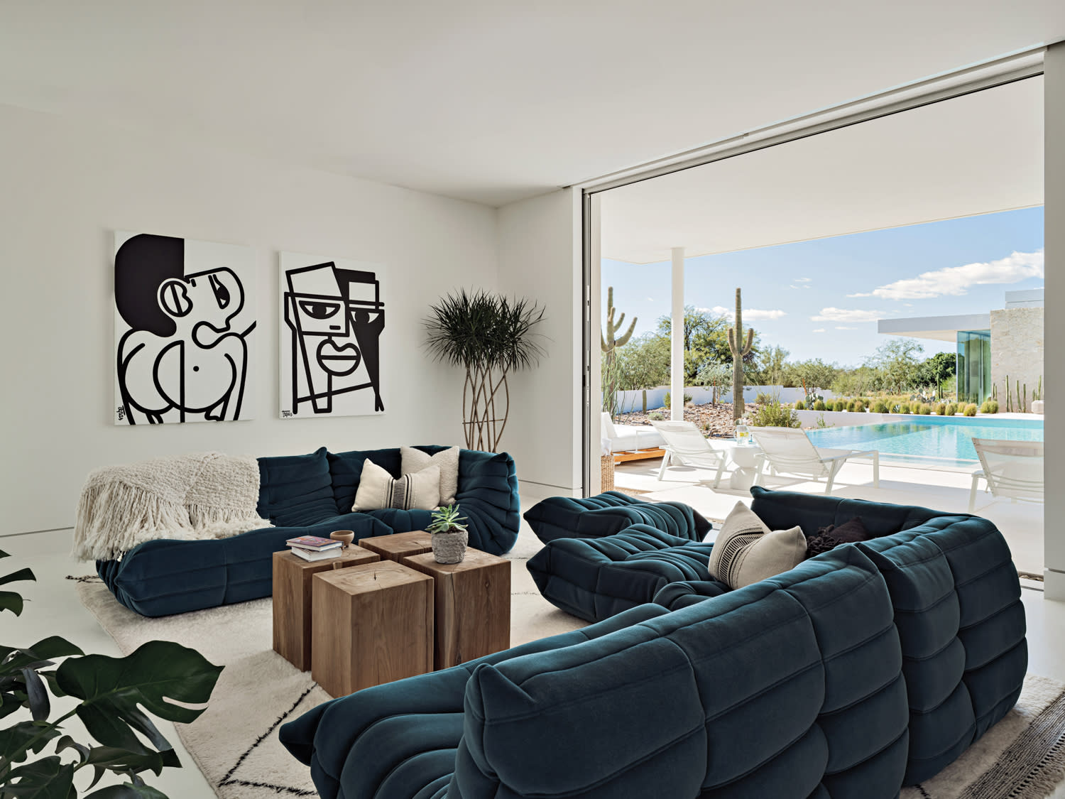modern pool house living room with abstract artwork and a blue sofa