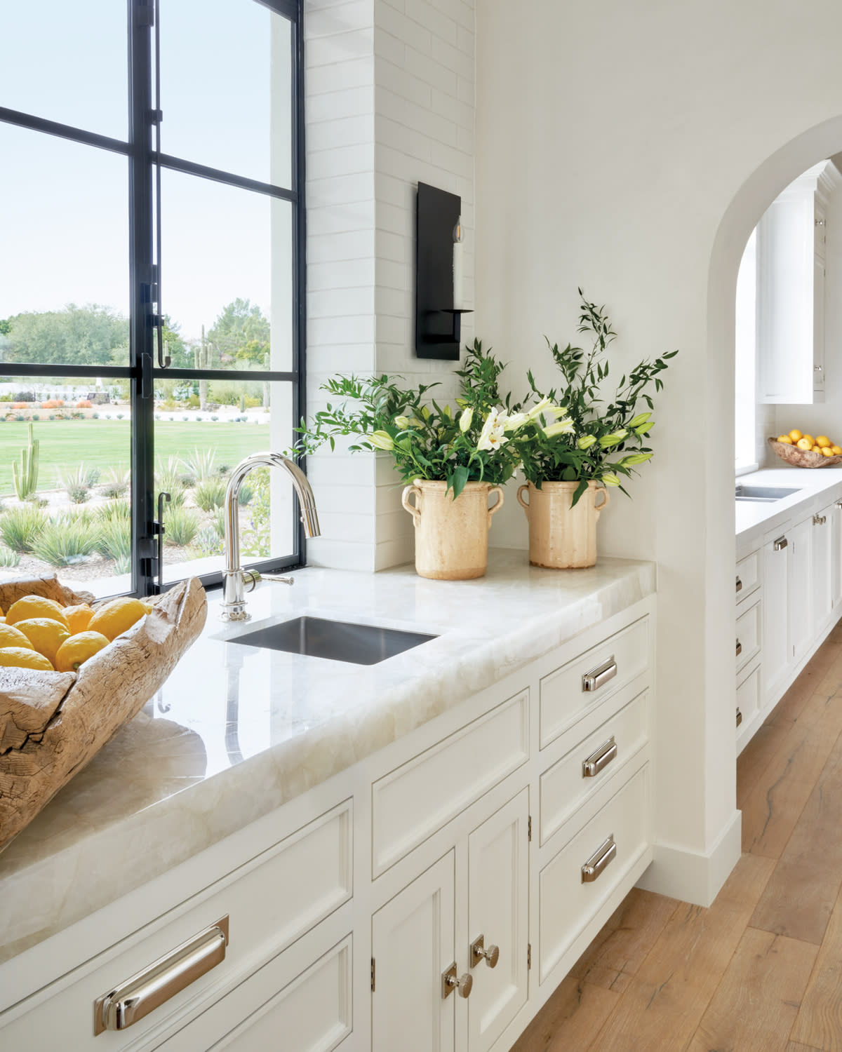 white quartz-topped ktichen cabinetry with black steel window overlooking yard