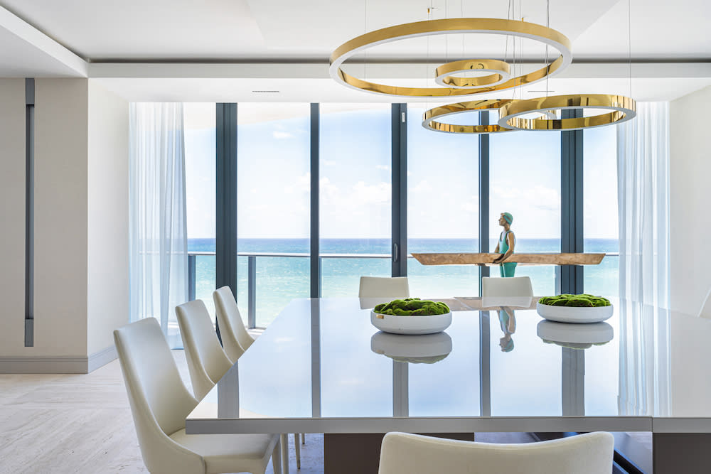 A cozy dining room featuring a table and chairs, with a stunning view of the ocean in the background.