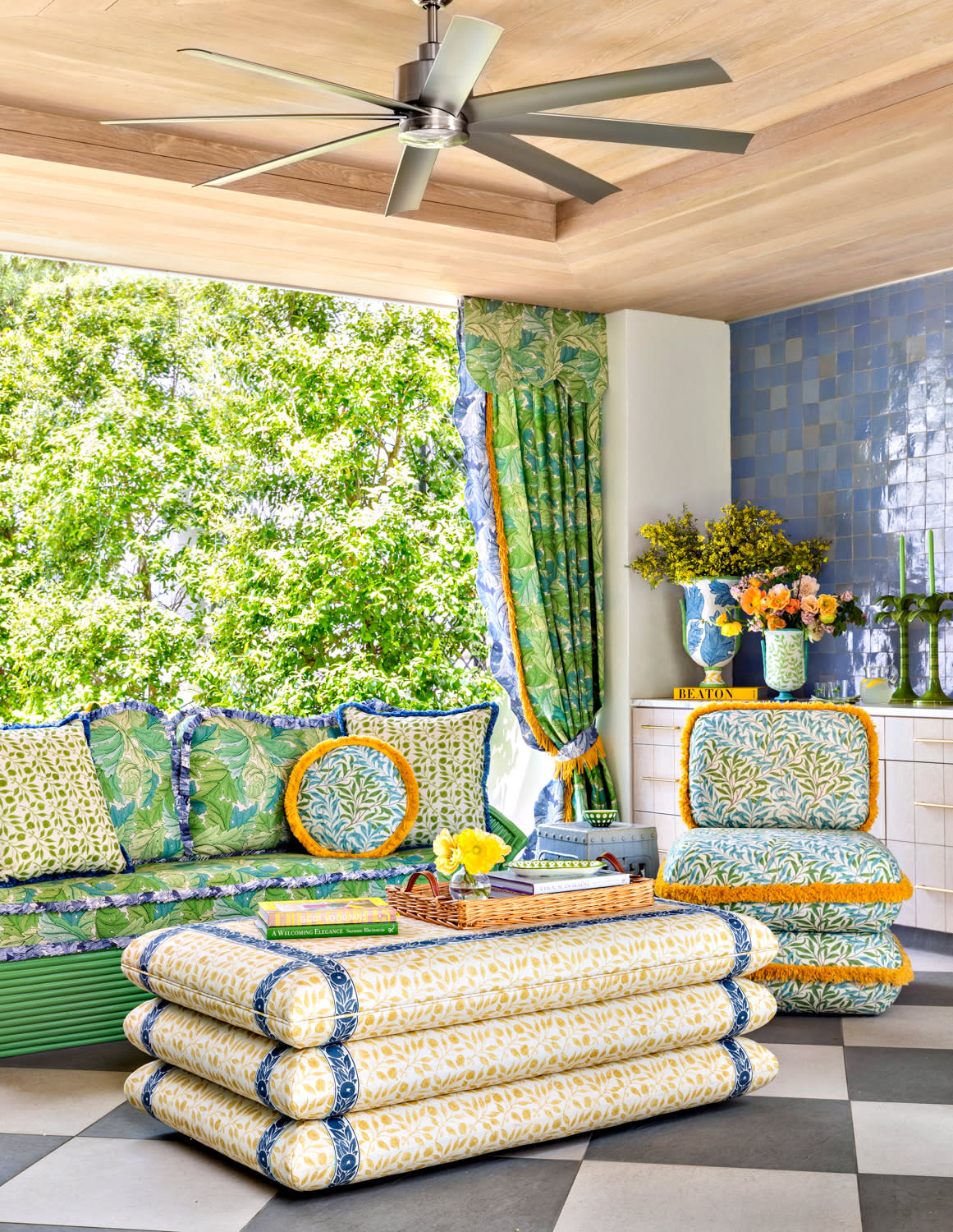 blue, green, and yellow patterned fabrics are on the furnishings in this checkerboard floored patio