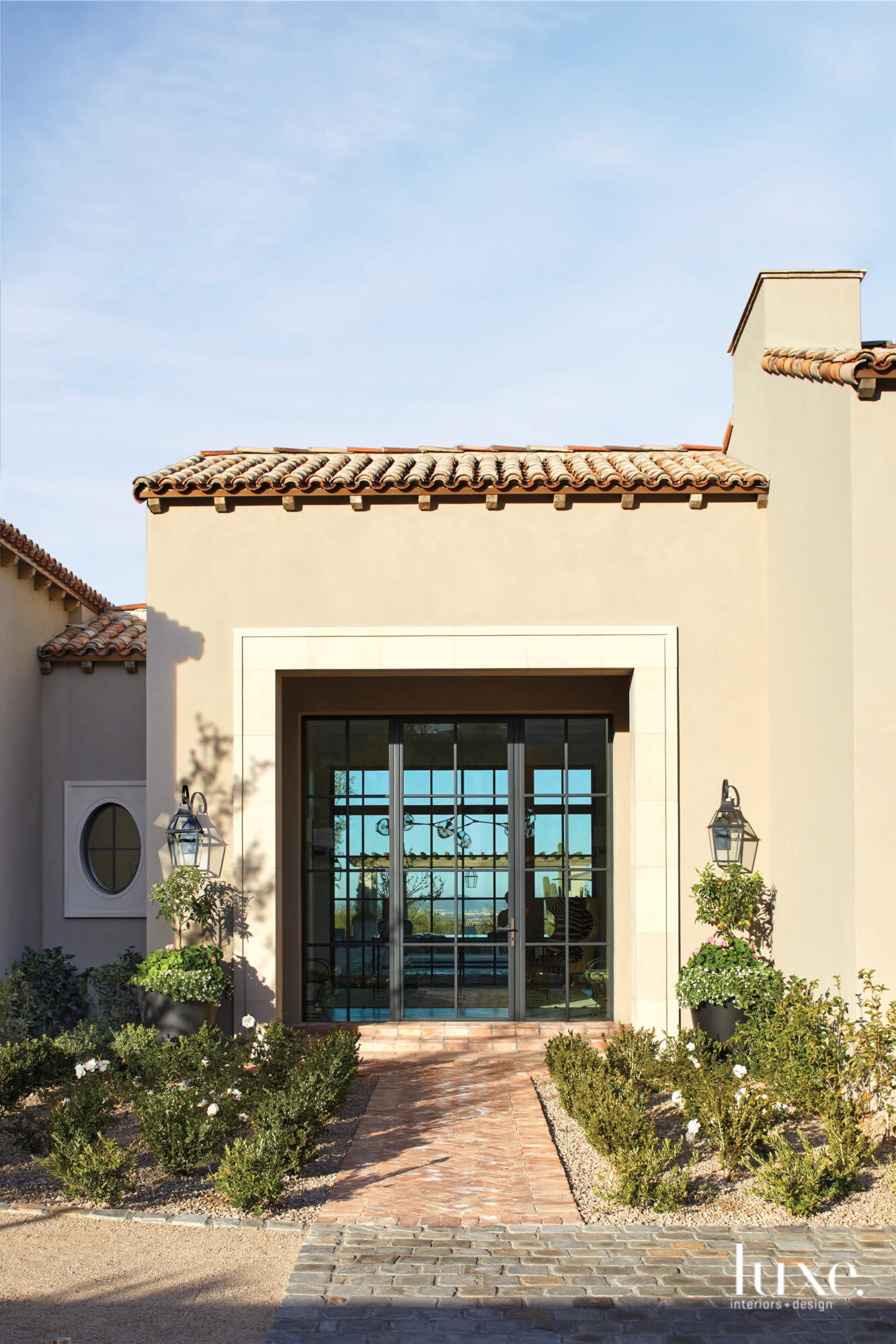 Landscaping frames the entrance to this Mediterranean-style home