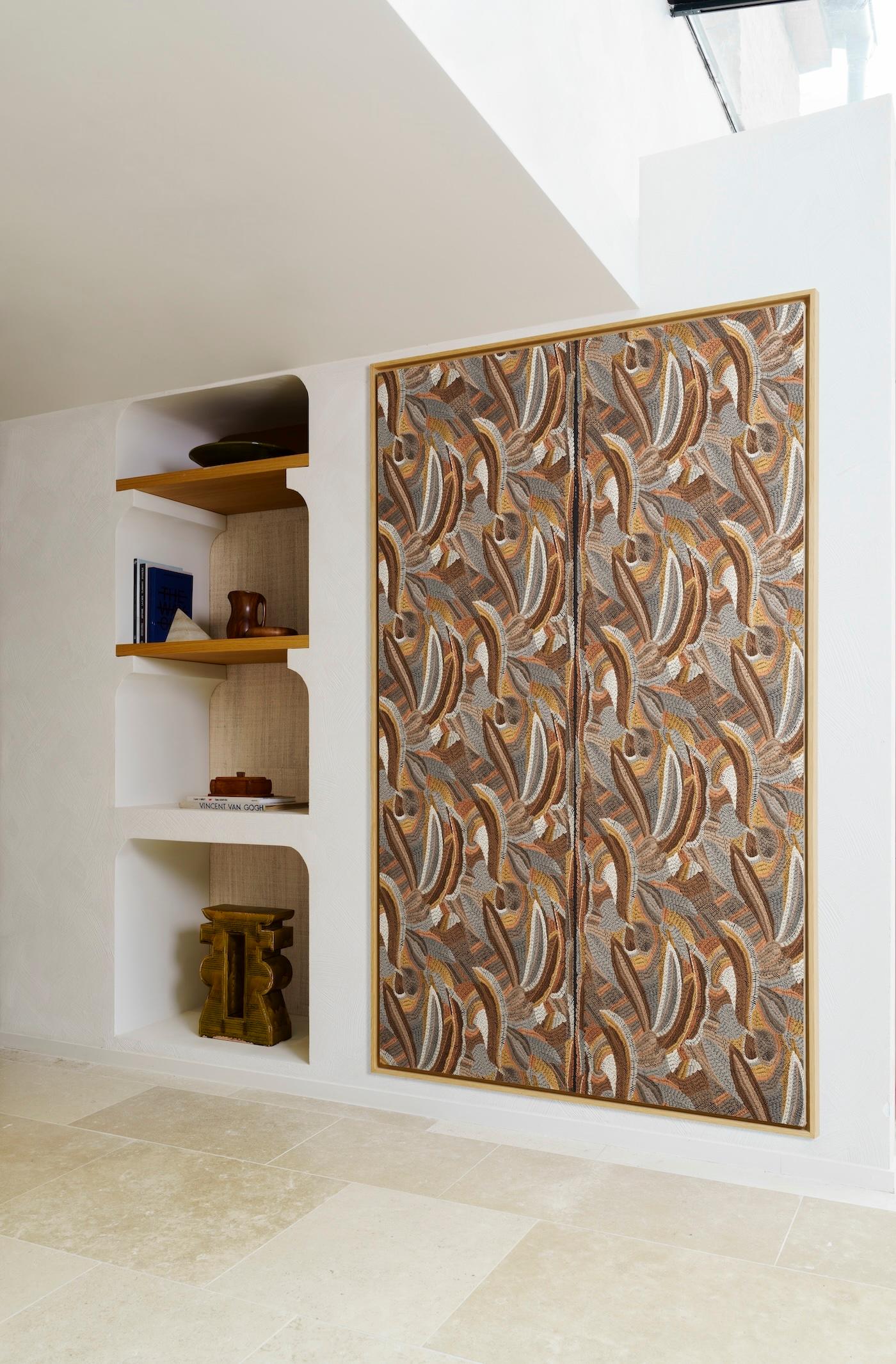 Closet with intricate brown and gold abstract pattern doors beside white shelves with books and pottery. Modern, elegant interior design.