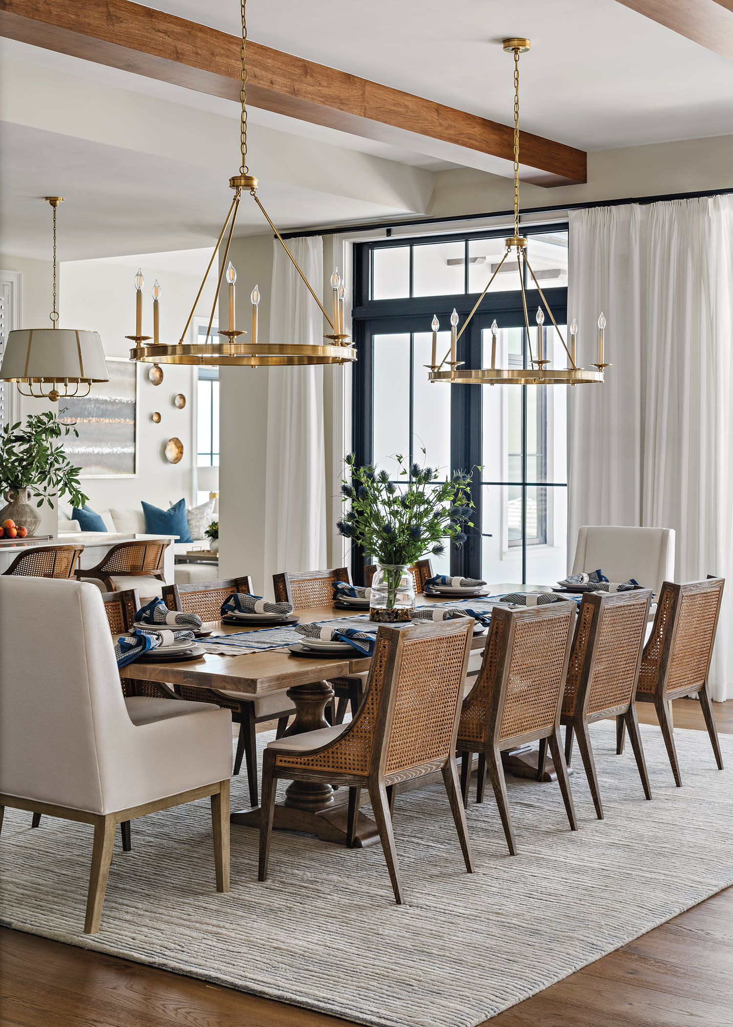 Elegant dining room with a large wooden table, surrounded by wicker chairs and upholstered end chairs